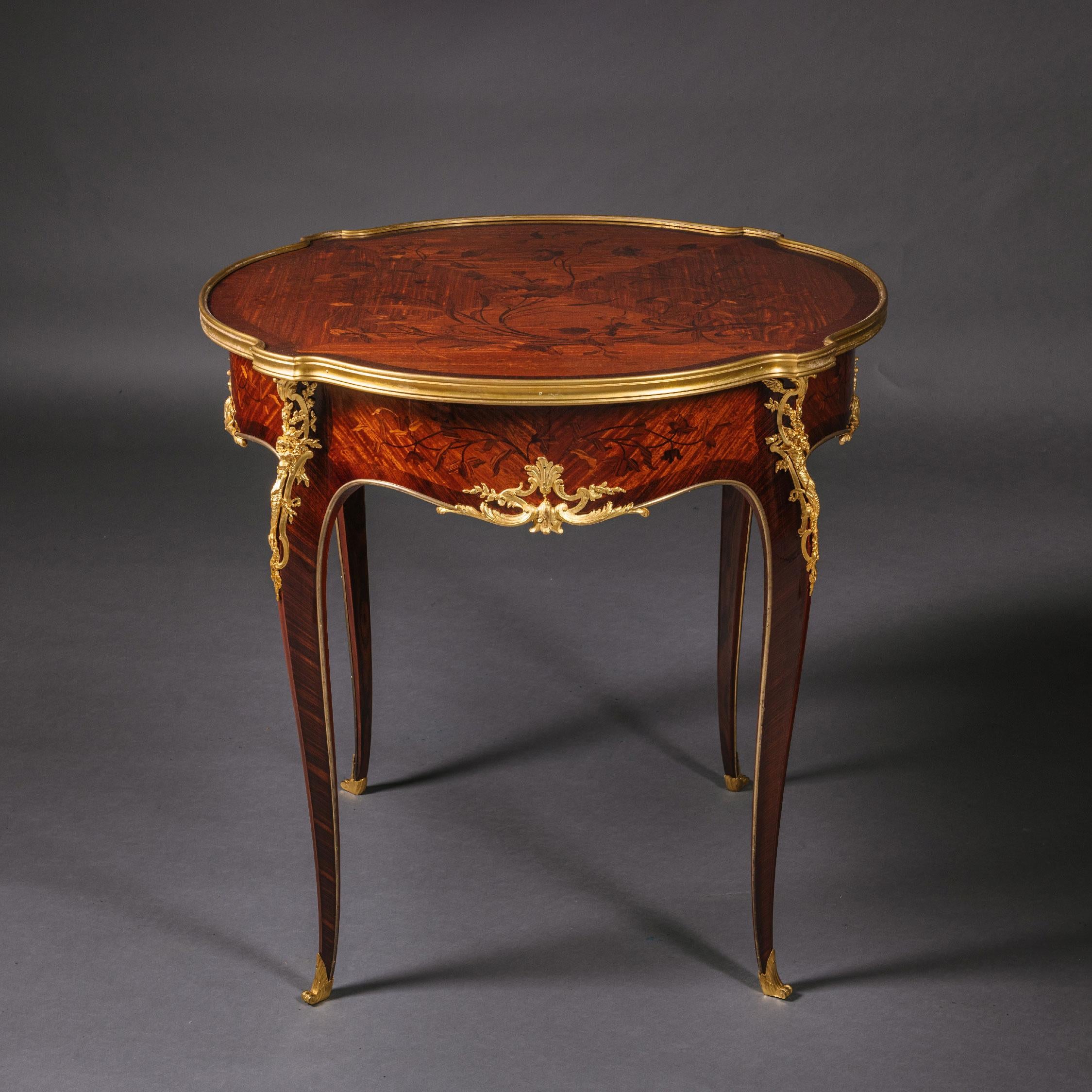 A gilt-bronze Marquetry Inlaid Gueridon, attributed to Emmanuel Zwiener.

This large gueridon or occasional table has a beautiful quarter veneered top which is inlaid with flower sprays. The frieze has conforming marquetry and is centred to each