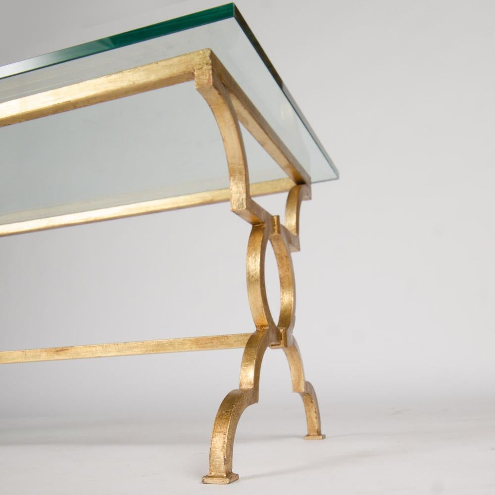 A beautiful gilt iron open rectangular glass top coffee table, framed with ring motif legs and a single stretcher after Gilbert Poillerat, France. This table is made in our workshops and is available in custom sizes.