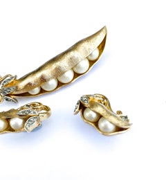 Spilla e orecchini in metallo dorato, perle finte e pasta, Trifari, anni '60.