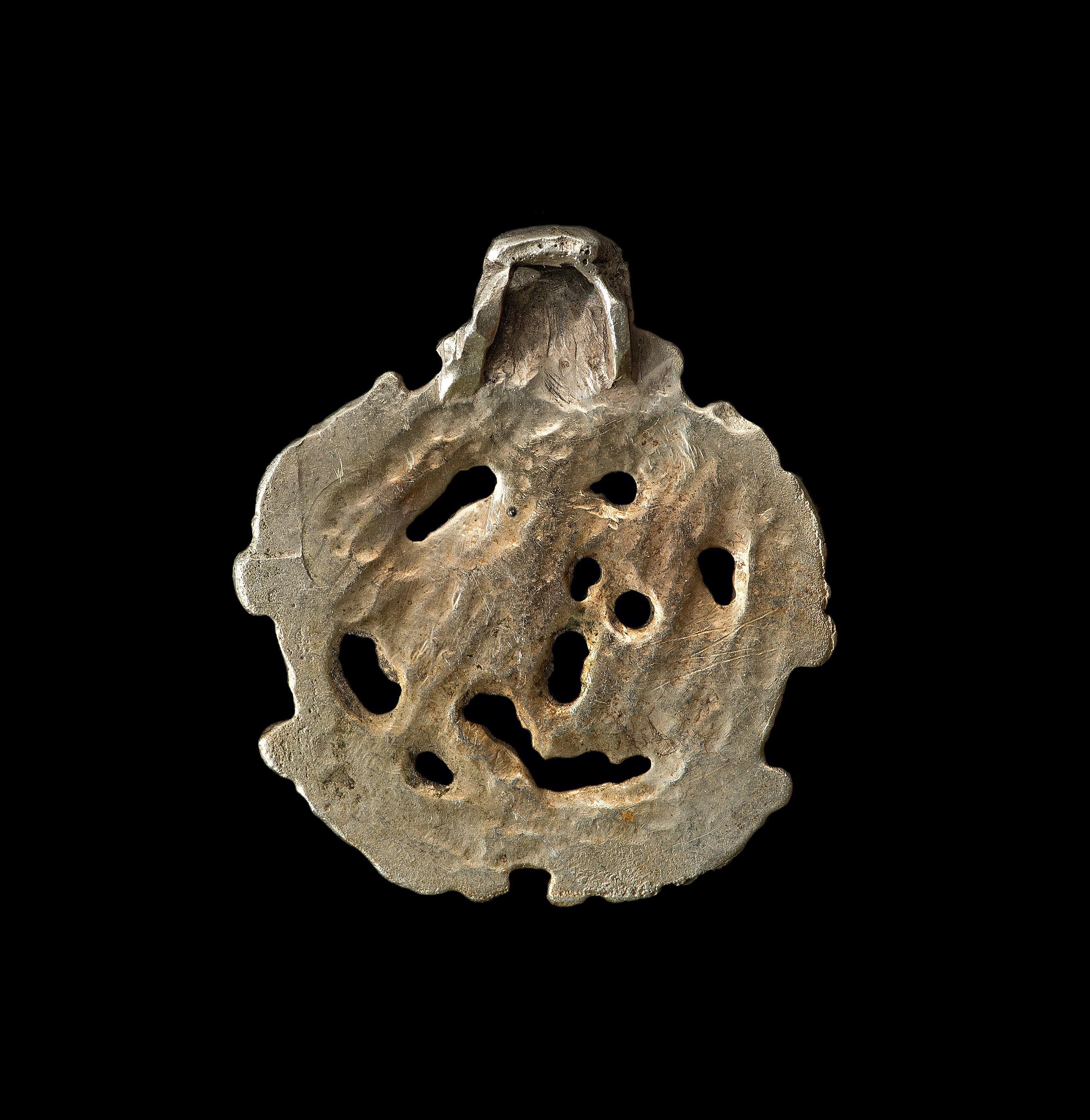 Origin: Viking inhabited area of Europe.

Gilt silver. A Borre-type concave-section pendant with integral suspension loop. The openwork plaque with three-band border and four beast-head panels, internal stylized zoomorphic beast.

Measures: