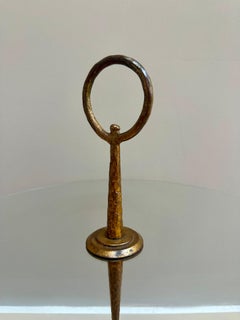 Una mesita auxiliar circular de hierro forjado dorado, diseñada por Giovanni Banci para Hermès