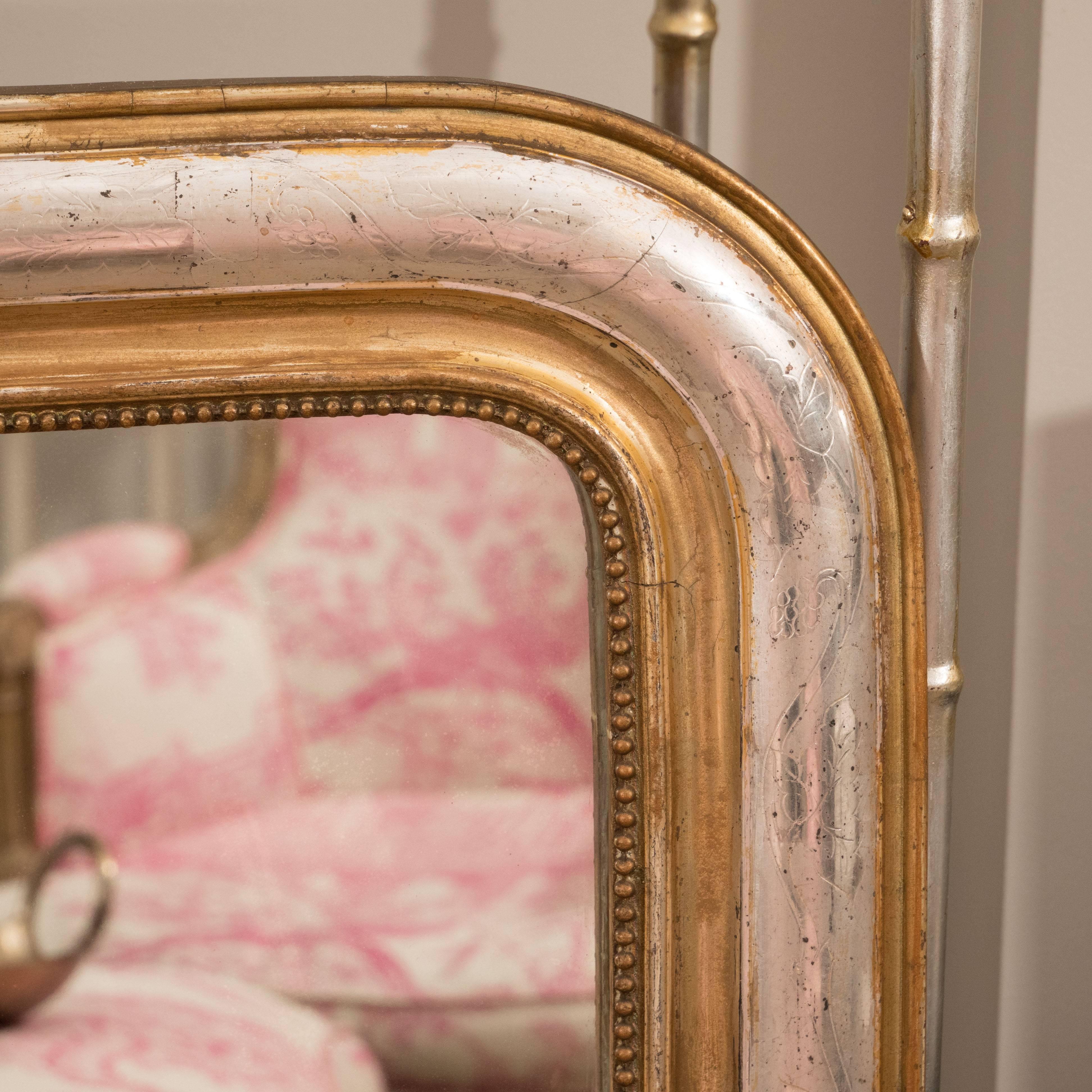 This Classic Louis Philippe mirror is unique in that it is finished in both silver leaf gold leaf. It features an inner beaded molding and delicate leaf decorations on the frame. Its clean lines make it adaptable to both traditional and contemporary