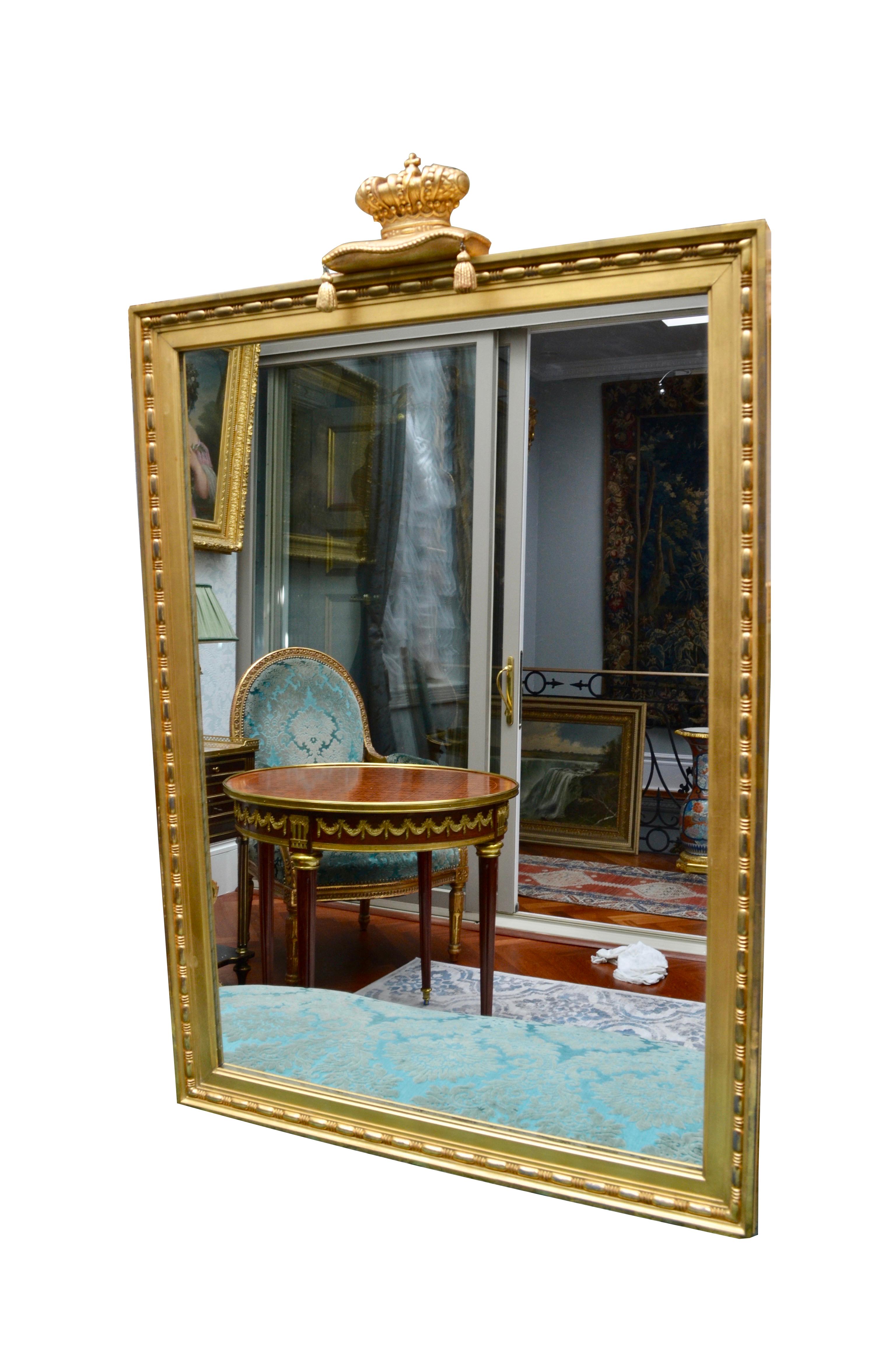 A simple and elegant Louis XVI style overmantle mirror presented in a giltwood beaded frame centred by a giltwood crown set on a giltwood tasseled cushion.