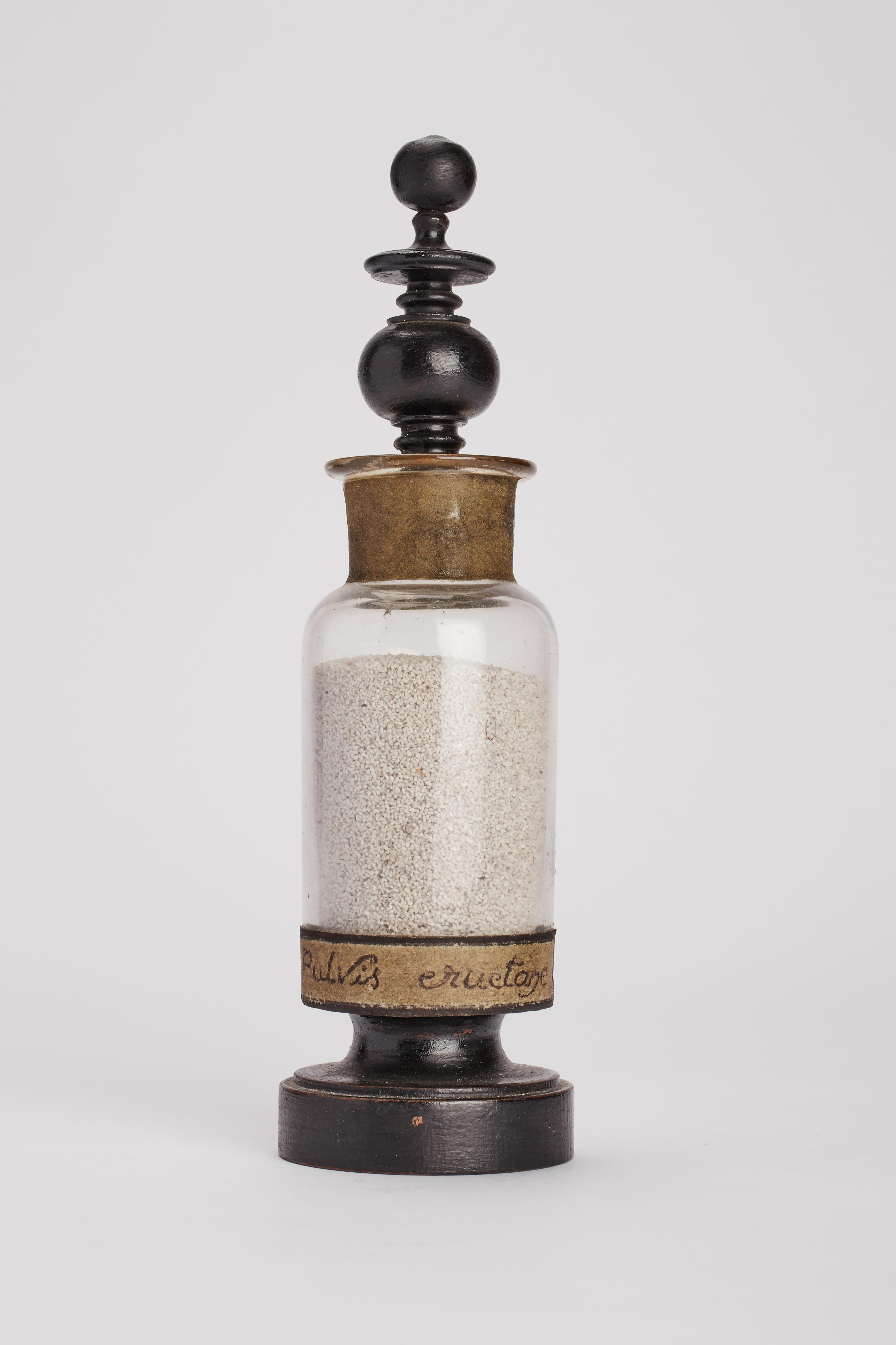 Specimen from wunderkammer, a glass ampoule with turned fruitwood lid painted black and label on the front. The paper label reads: Pulvis eructanea. France circa 1870.
