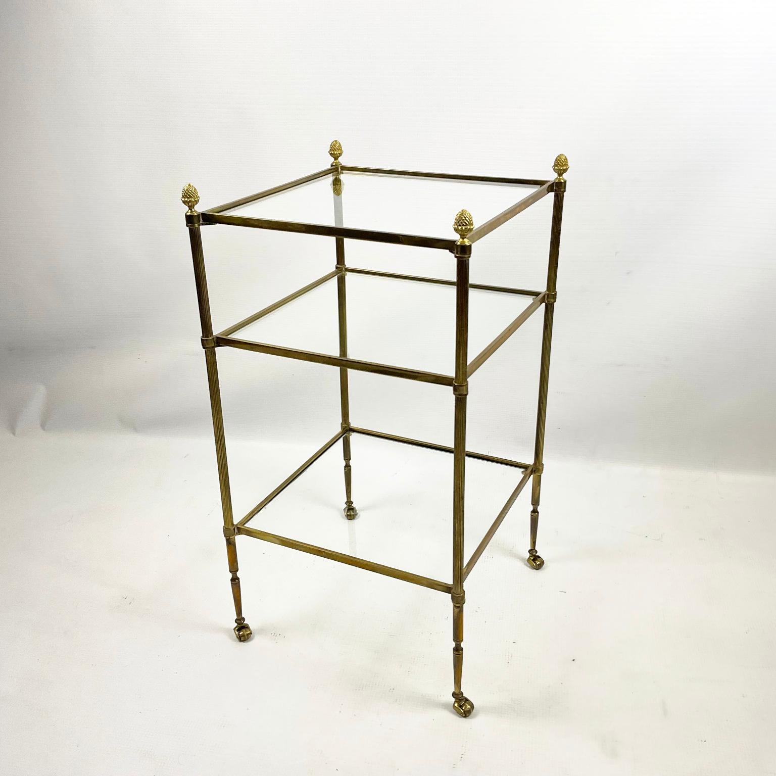 Small brass shelf or side table on wheels from the 1960s attributed to Maison Jansen
The mount is made of good-quality brass and topped with four decorative pine cones.
The three original glasses are made of low iron glass, which shows the quality
