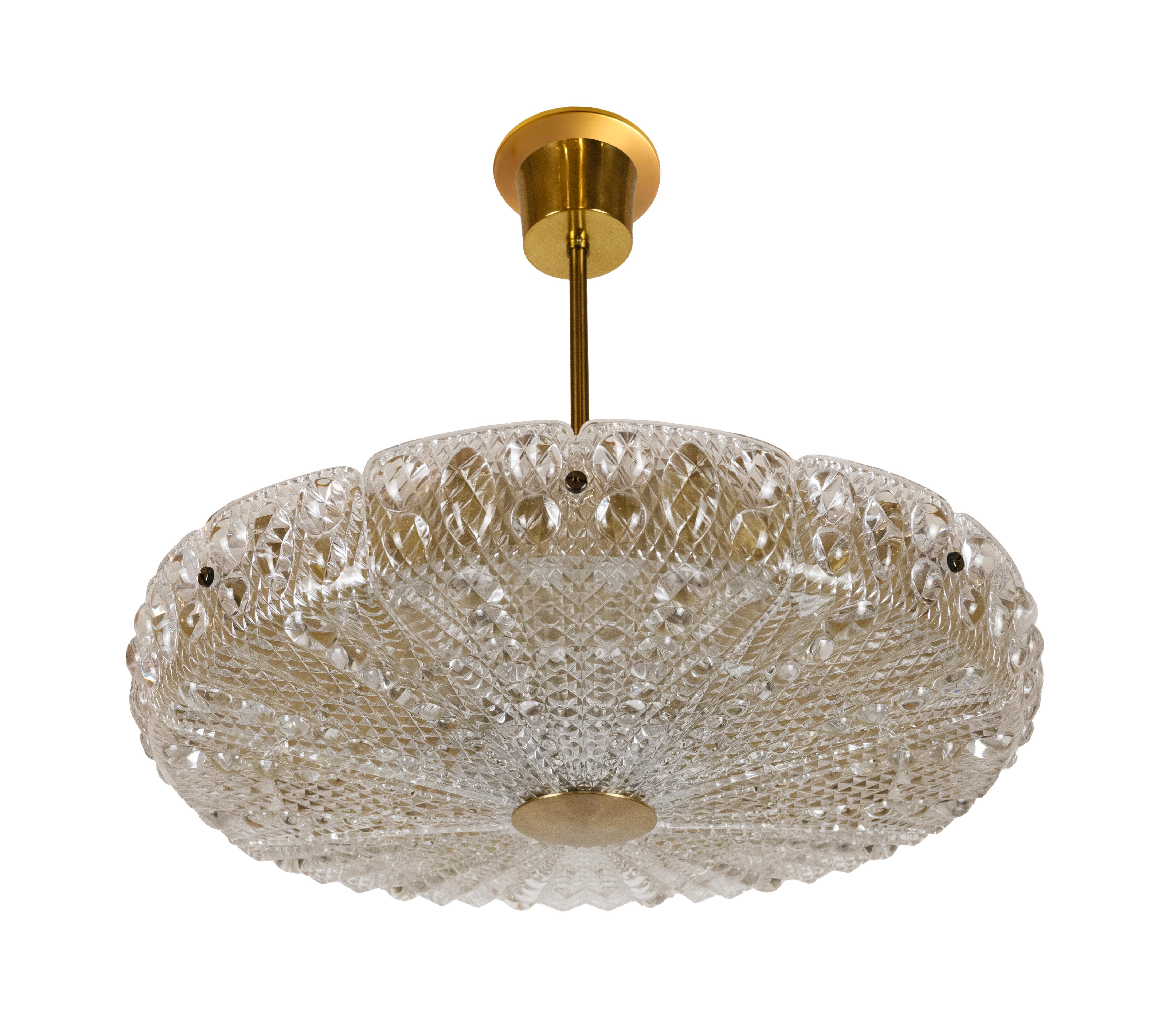 Un grande pendente in vetro e ottone disegnato da Carl Faugerlund per il produttore svedese Orrefors. Il vetro è fuso in 8 sezioni, ognuna delle quali nasconde una presa media, sostenuta da un unico stelo e da un baldacchino in ottone patinato.