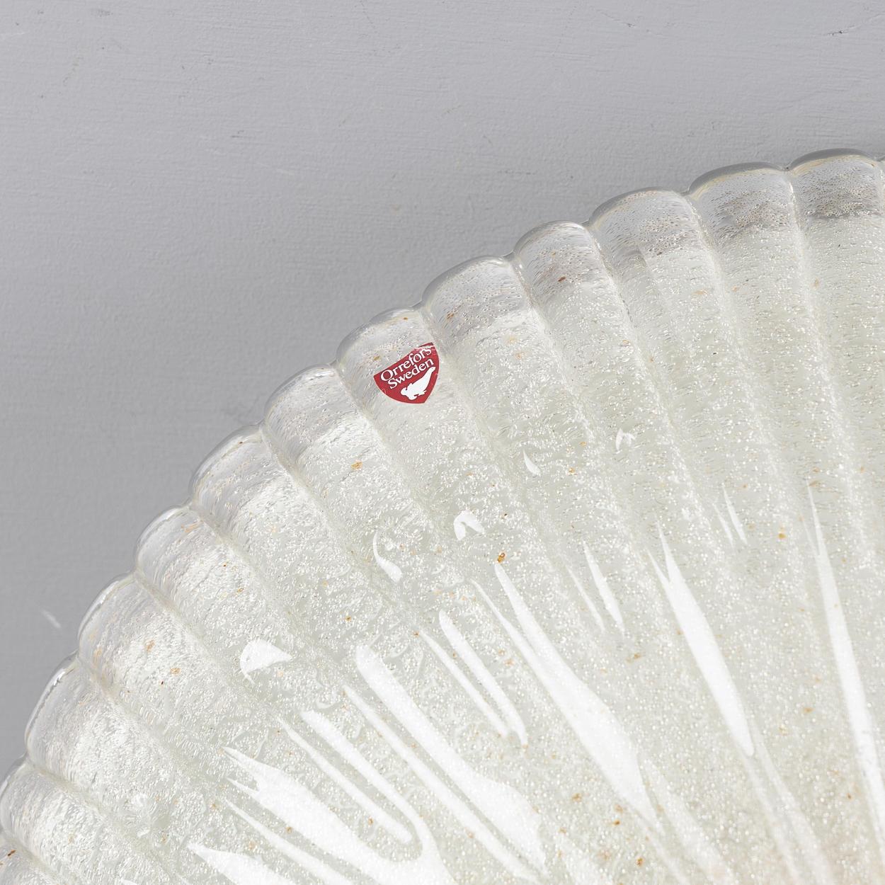 A cast glass flush mount by Swedish maker Orrefors. The fluted glass dish secured by minimal brass finial. Circa 1960, price includes new UL wiring