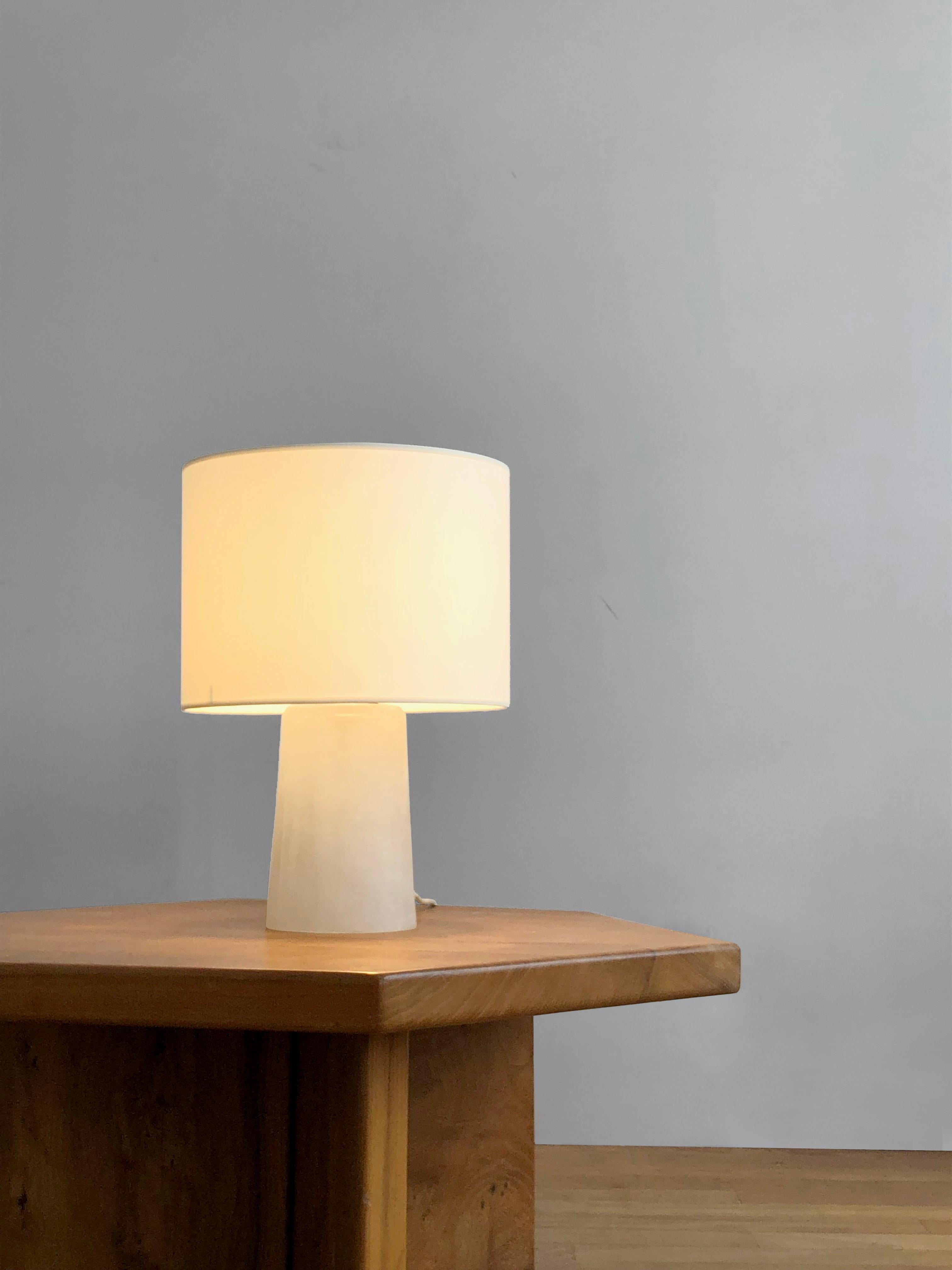 A simple, sensual and imposing table lamp, Space-Age, Post-Modernist, Shabby-Chic, massive base in white granite Murano glass, white cylindrical lampshade, Cenedese signature acid-etched inside the lamp base, by Cenedese, Murano, Italy 1960.

The