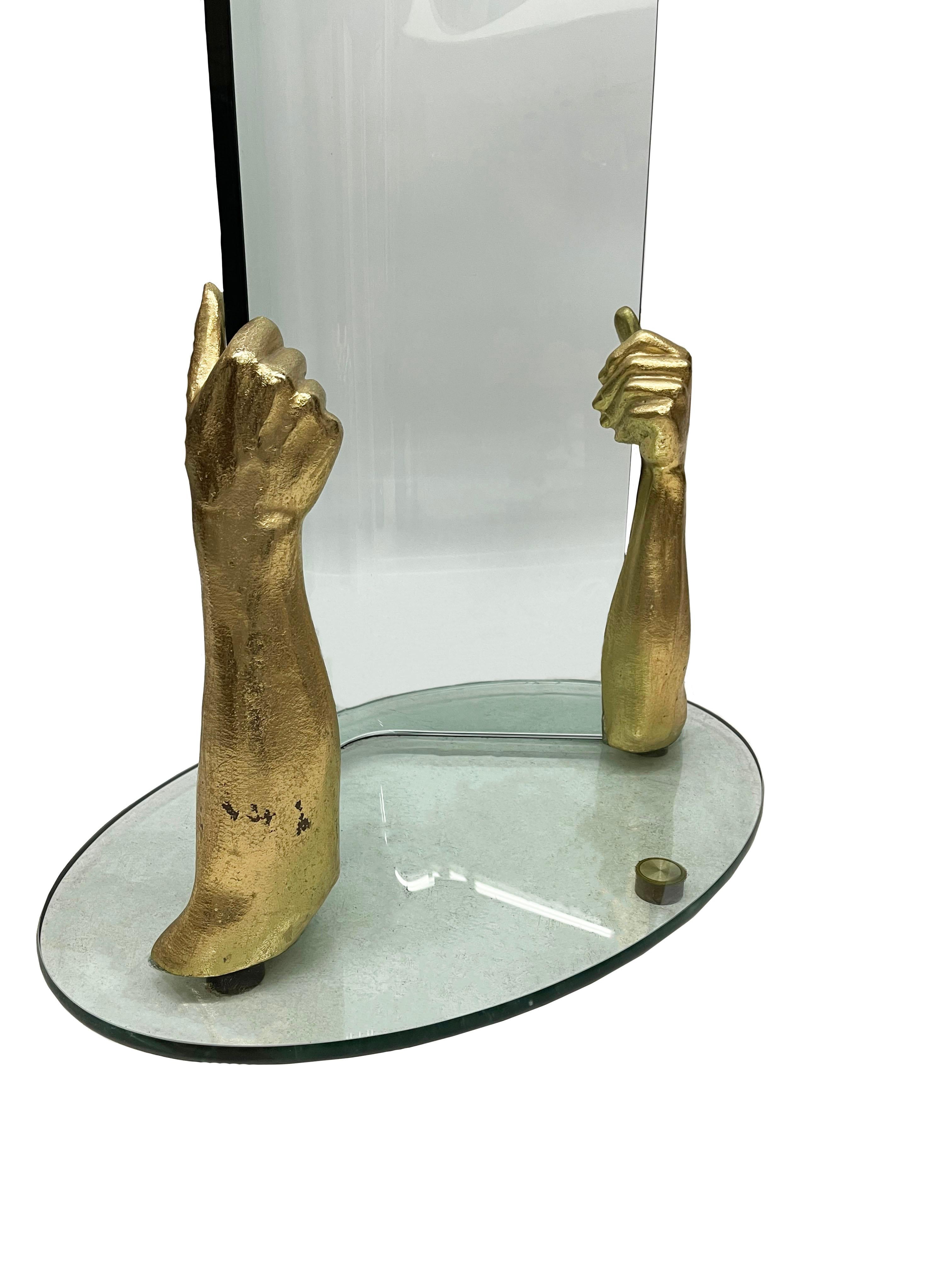 Standgarderobe aus Glas und Bronze

Moderner Garderobenständer aus dickem Glas in Form eines Baumes, mit gebogenem Glas. Unten 2 bronzene, vergoldete Arme, die als Hände das Glas hochhalten. Die Garderobe ist 181,5 cm hoch, der Fuß ist oval und