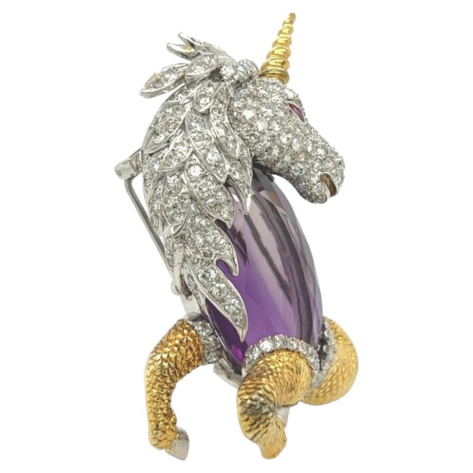 A 14 karat yellow and white gold, amethyst, ruby and diamond brooch.  Designed as a mythical creature with the head and forelegs of a unicorn and a the tail of a fish, the white gold head pave set all over with approximately one hundred twenty three