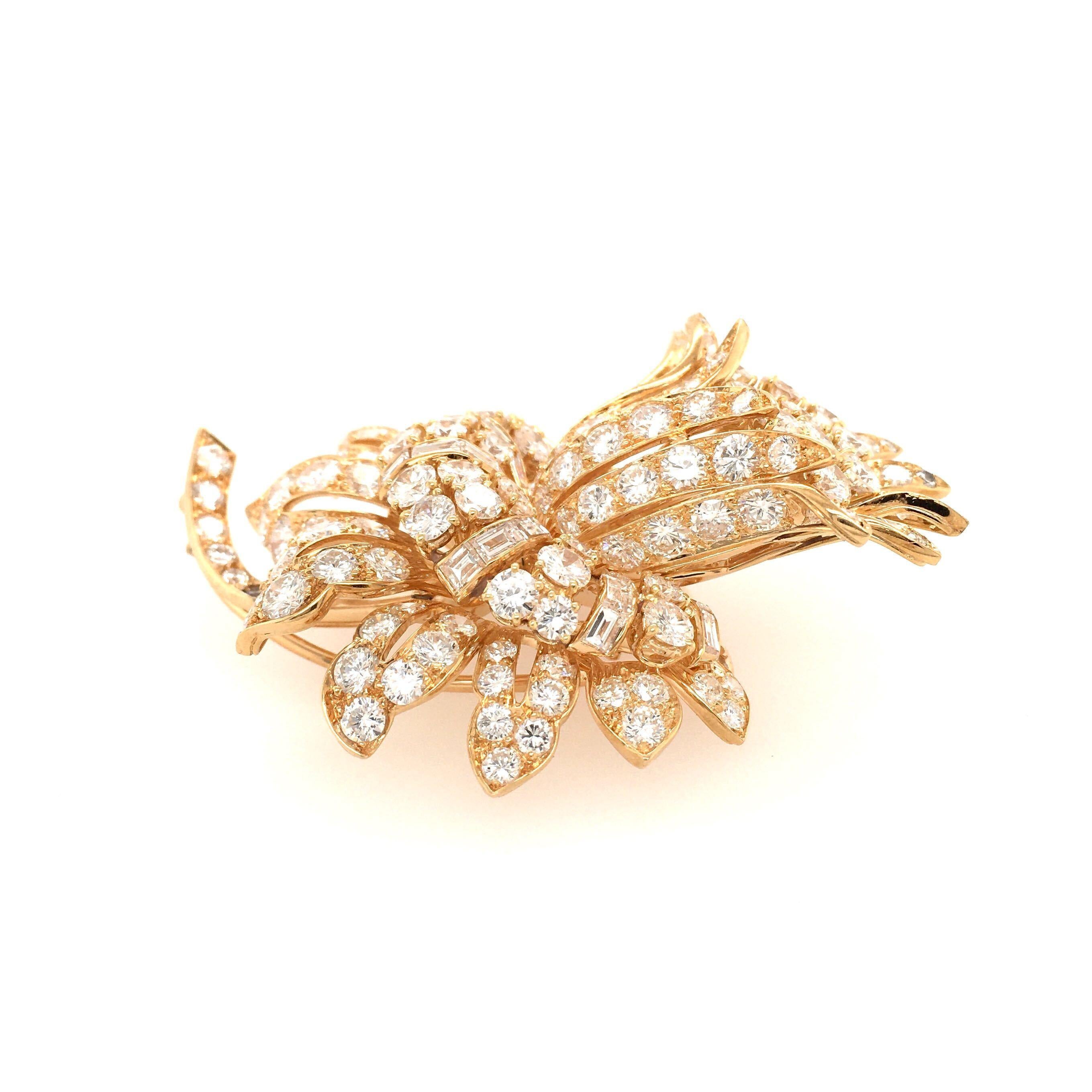 An 18 karat yellow gold and diamond brooch, French, 1960s.  Designed as a flower set with approximately one hundred forty six  brilliant cut diamonds of various sizes and twenty two  baguettes of various sizes.  Total diamond weight approximately