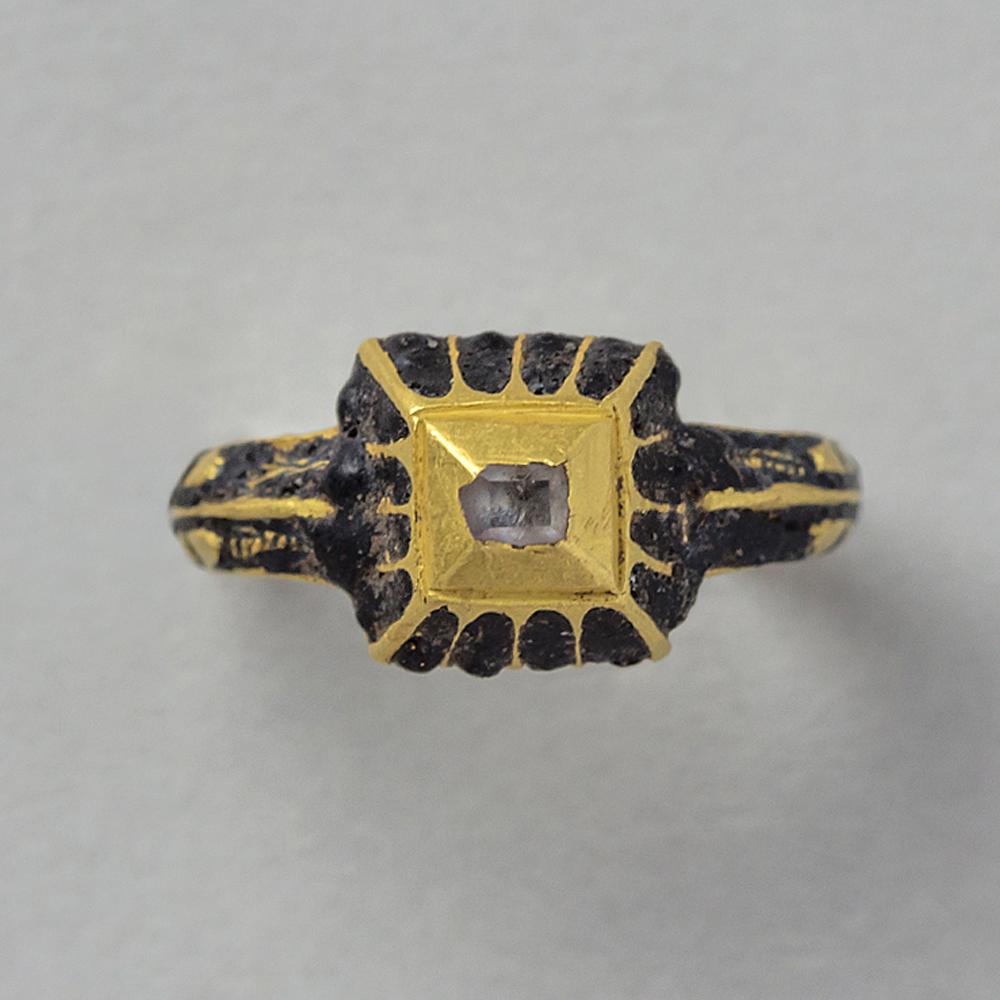 One small gold ring set with a table cut diamond with dark blue champlevé enamel in stripes in the arcades of a box bezel and in the shank, Western European and found in the Netherlands, (Pan-00052292).

weight: 2.7 grams
ring size: 1 3/4 USA