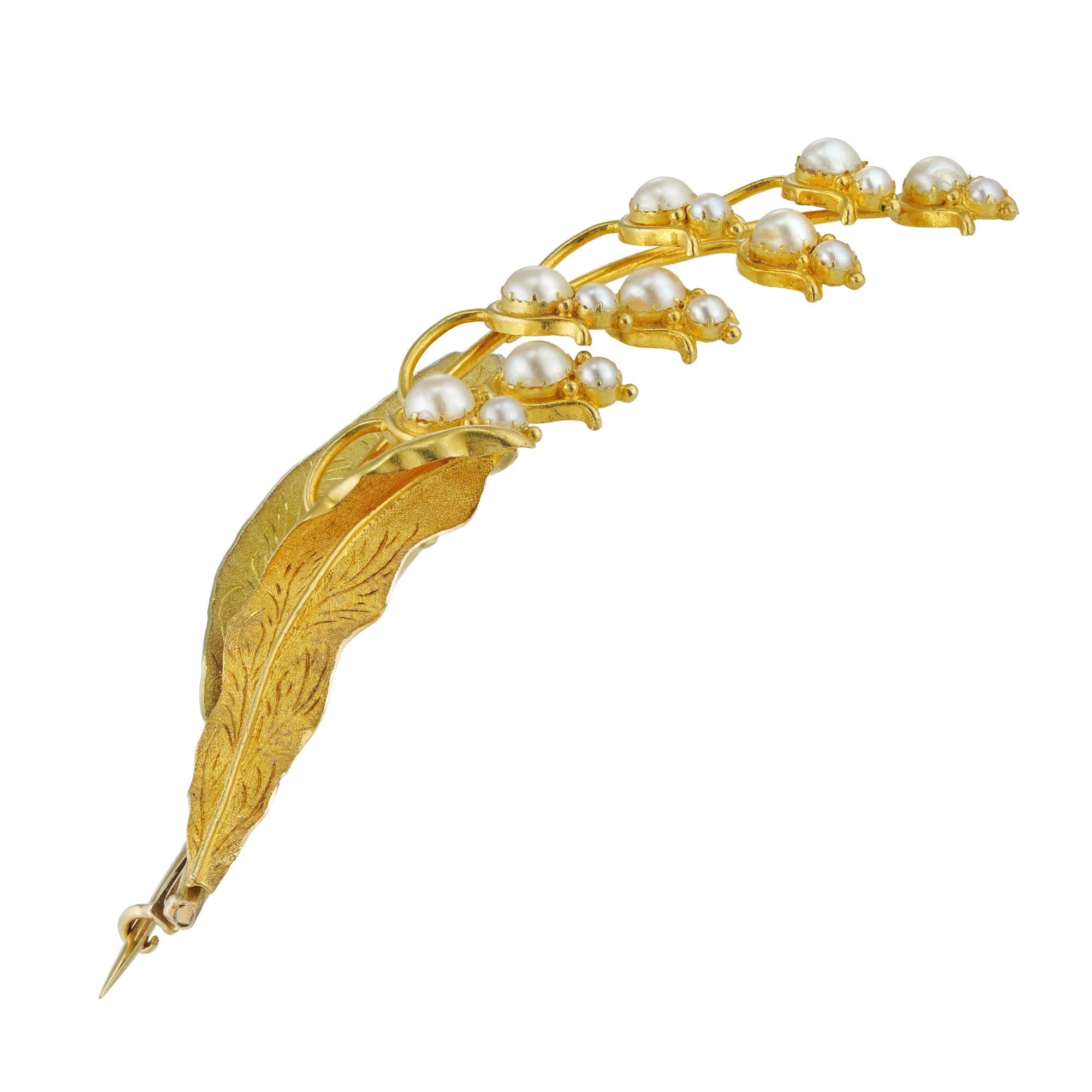A gold and half-pearl spray brooch, in the form of a lily of the valley spray, the leaves with chased two colour gold mounts, the eight flowers each set with two split pearls, circa 1830, with later brooch fitting, measuring approximately 8 x 2.5