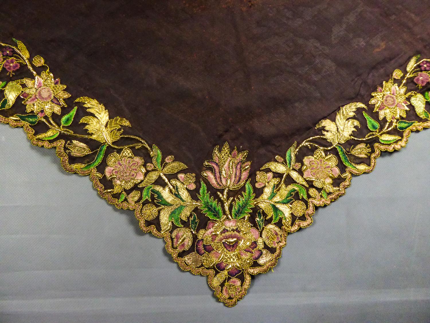 Prima metà del XVIII secolo
Germania o Europa

Fichu o fazzoletto palatino in garza di seta marrone densamente ricamato e smerlato con volute di fiori esotici. Abile ricamo professionale in guipure, arricciato e goffrato con fili di lamé d'oro. Una