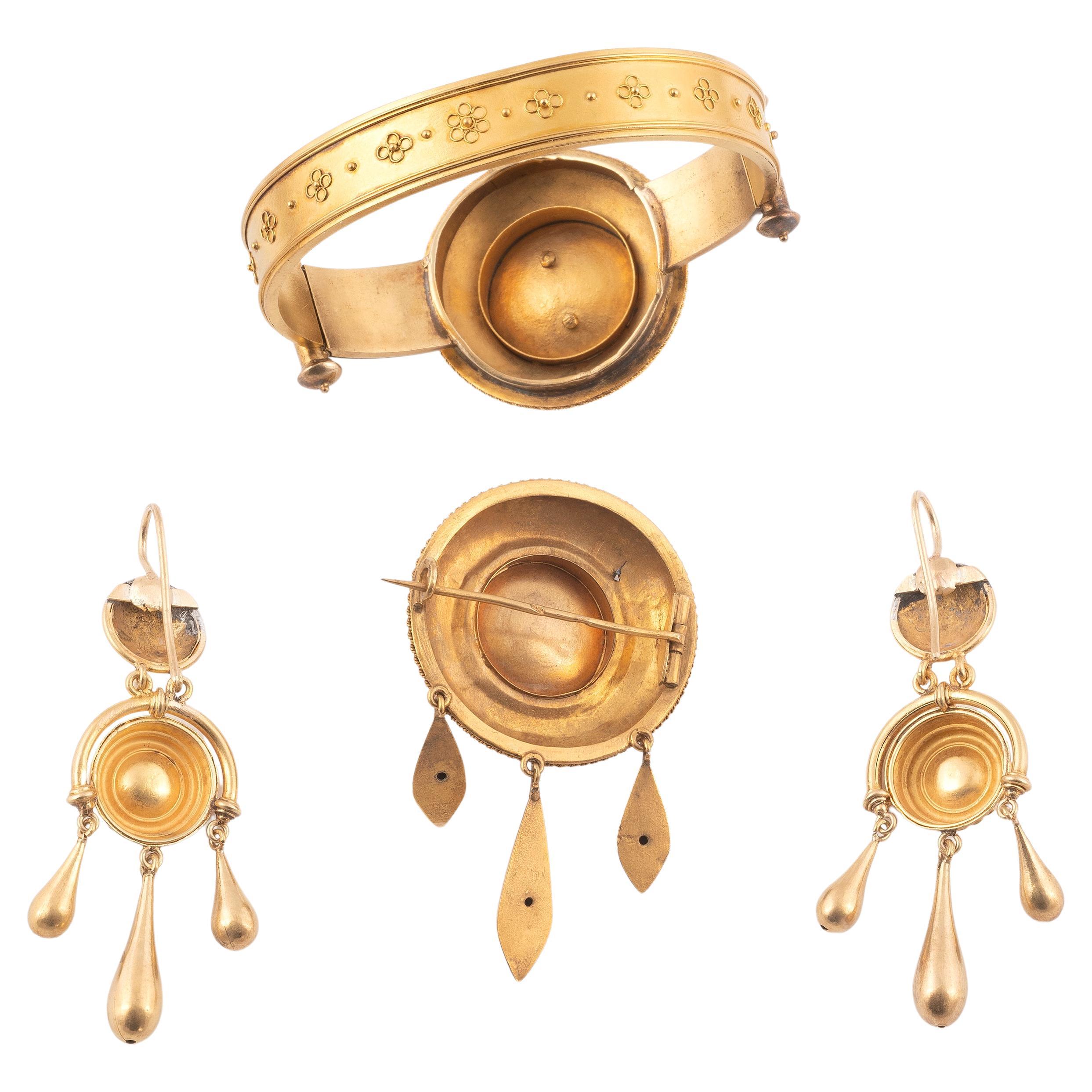 Composed of a broad hinged bangle with applied grape and vine leaf, within rectangular borders, together with a pair of matching earrings, and an oval brooch with engraved detail, in a fitted case, diameter 6cm, brooch length 5cm, earring length