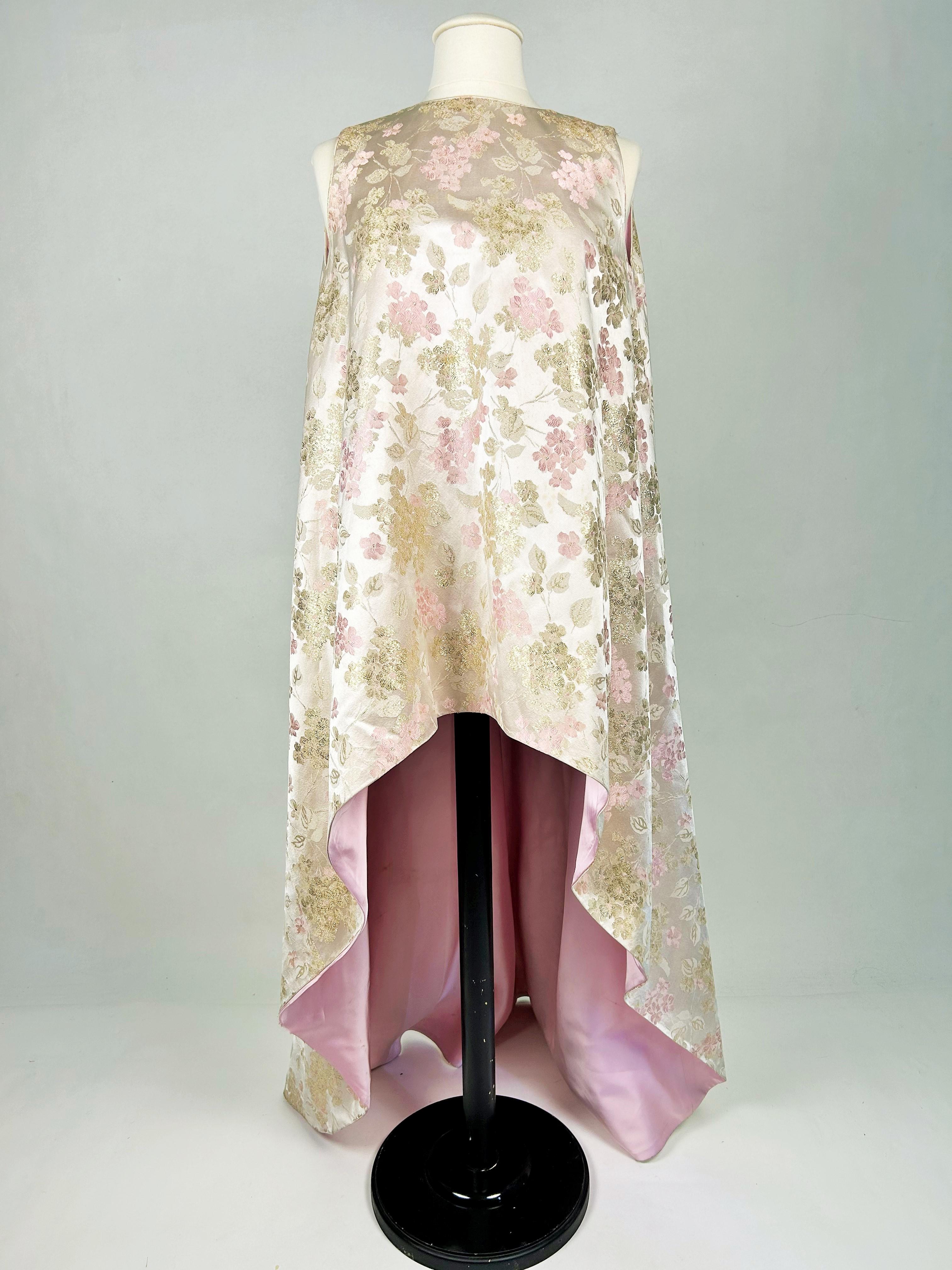 Vers 1968-1970. États-Unis
Dans le style de Cristobal Balenciaga, une robe péplum américaine avec une traîne en queue de paon, labellisée By Peer, taille 8 et datant des années 1960. Ce modèle est peut-être basé sur un modèle de Balenciaga vendu aux