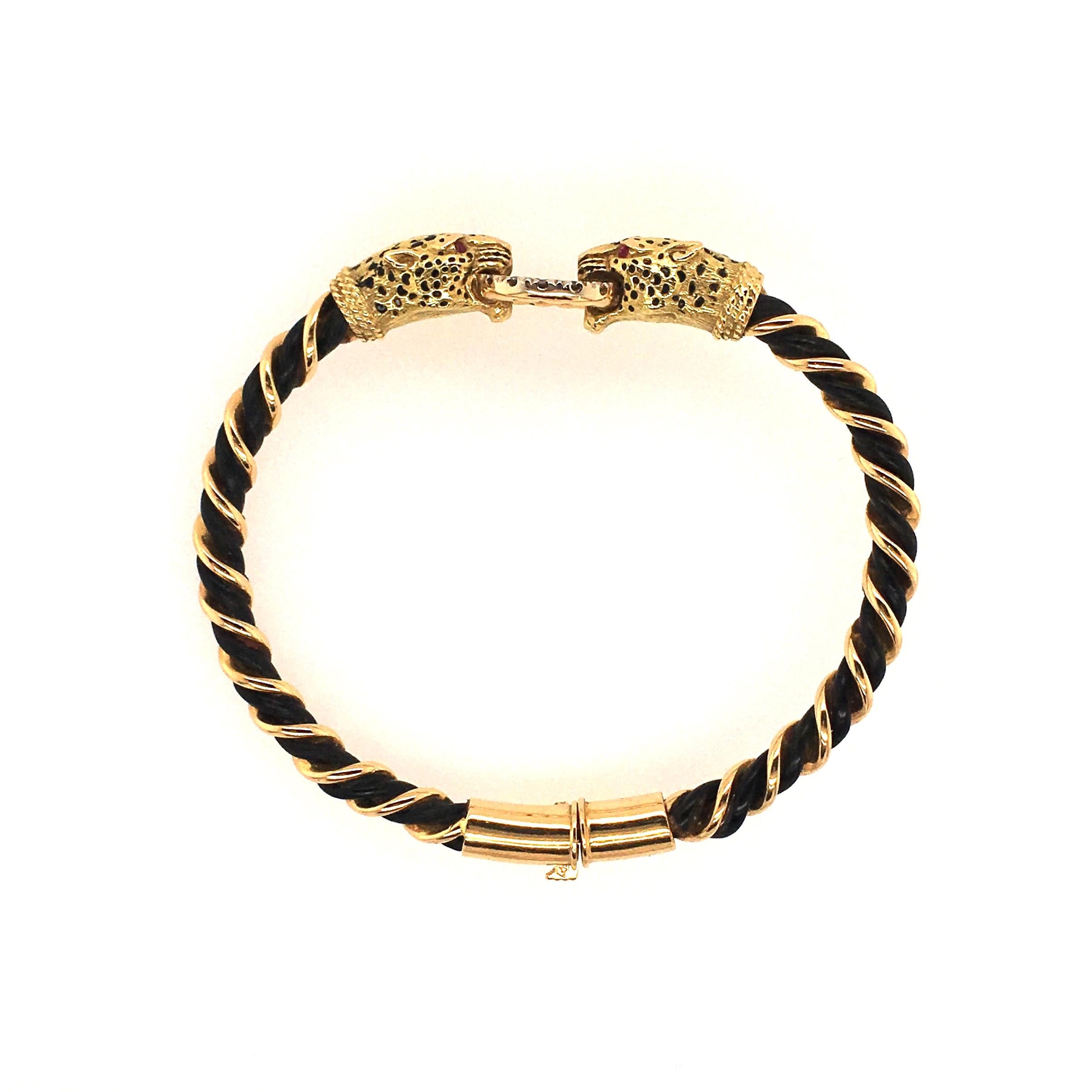 An 18 karat yellow gold, diamond, elephant hair and enamel bracelet. French. Attributed to Gay Frères. The hinged bangle designed as braided gold elephant hair, wrapped in gold wire, joined by two leopard heads, with black enamel spots, enhanced by