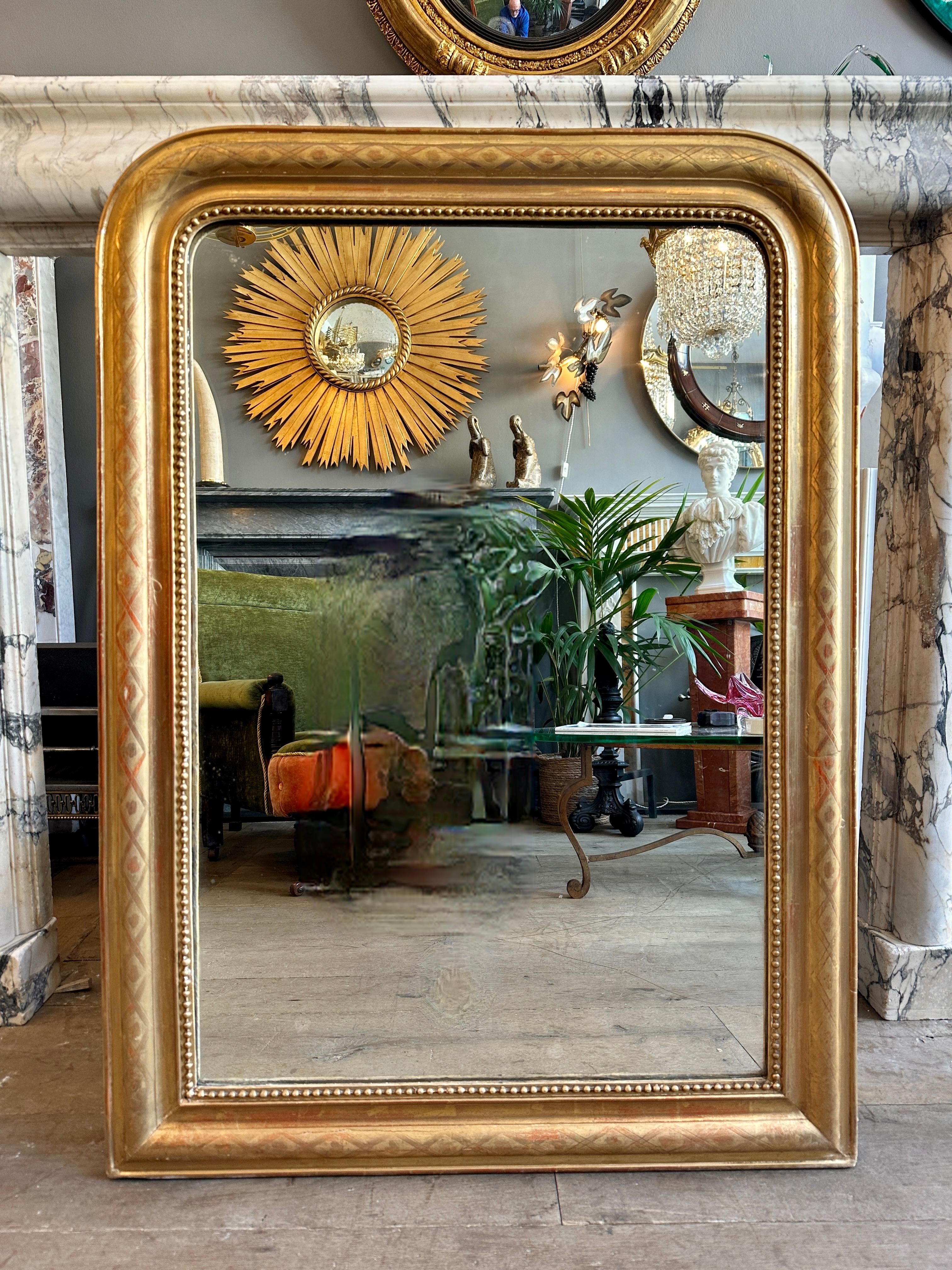 Miroir français ancien Louis Philippe, à couvercle bombé et doré. Patine dorée douce avec un motif géométrique sur le cadre, avec une glissière intérieure perlée. Il a conservé sa plaque de miroir en verre d'origine et son dos cartonné. Plaque avec