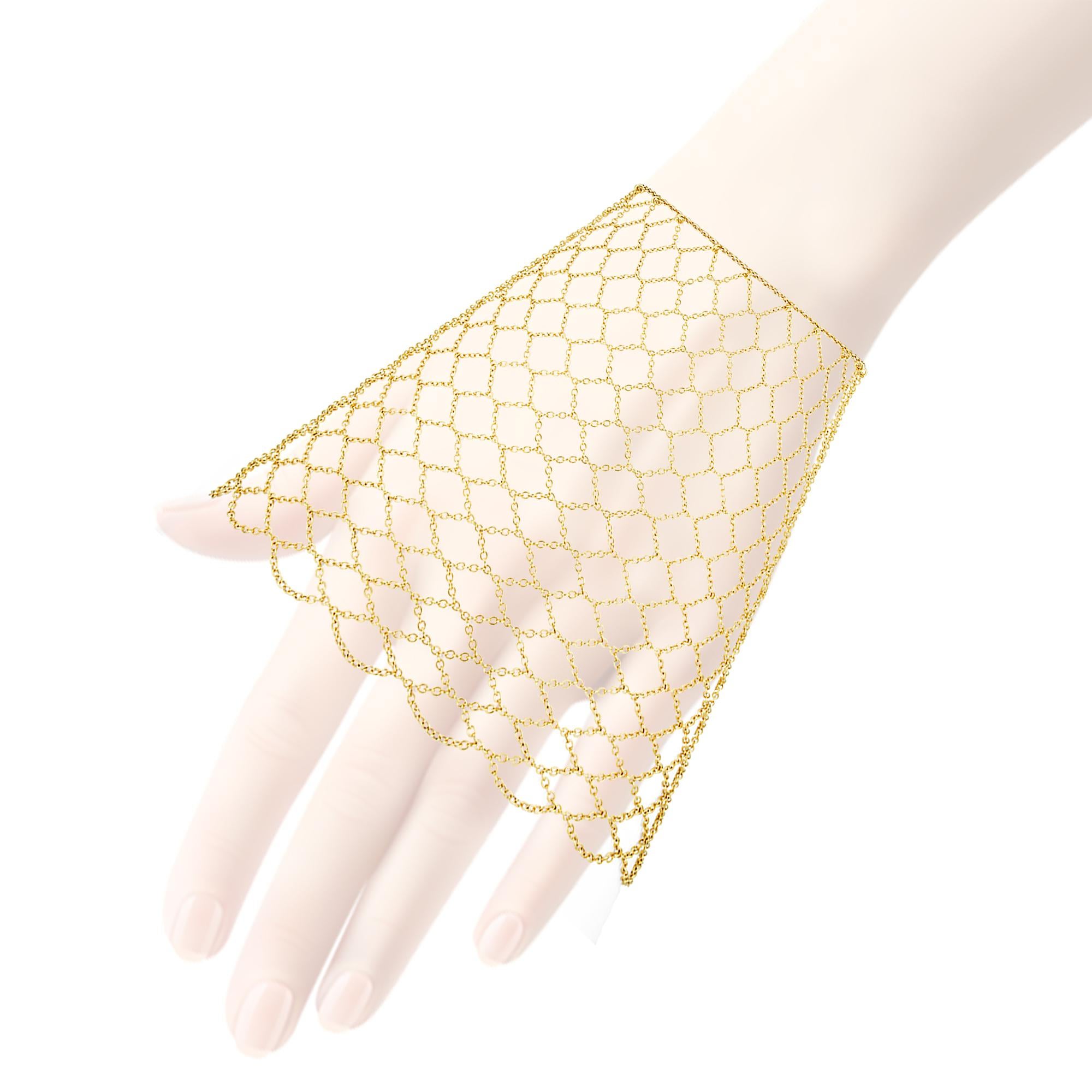 A wide gold Lucie Heskett-Bremhand hand chain cuff of fine open work mesh design bearing the Swiss common control mark for 18 gold,  measuring approximately 14x8.5cm, gross weight 16.6 grams

A gold hand chain cuff in perfect condition.

Should you