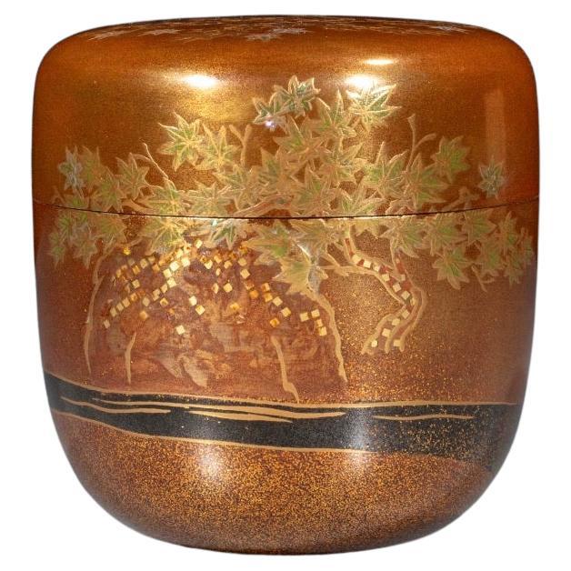 Un natsume laqué or avec des feuilles d
érable et un ruisseau
