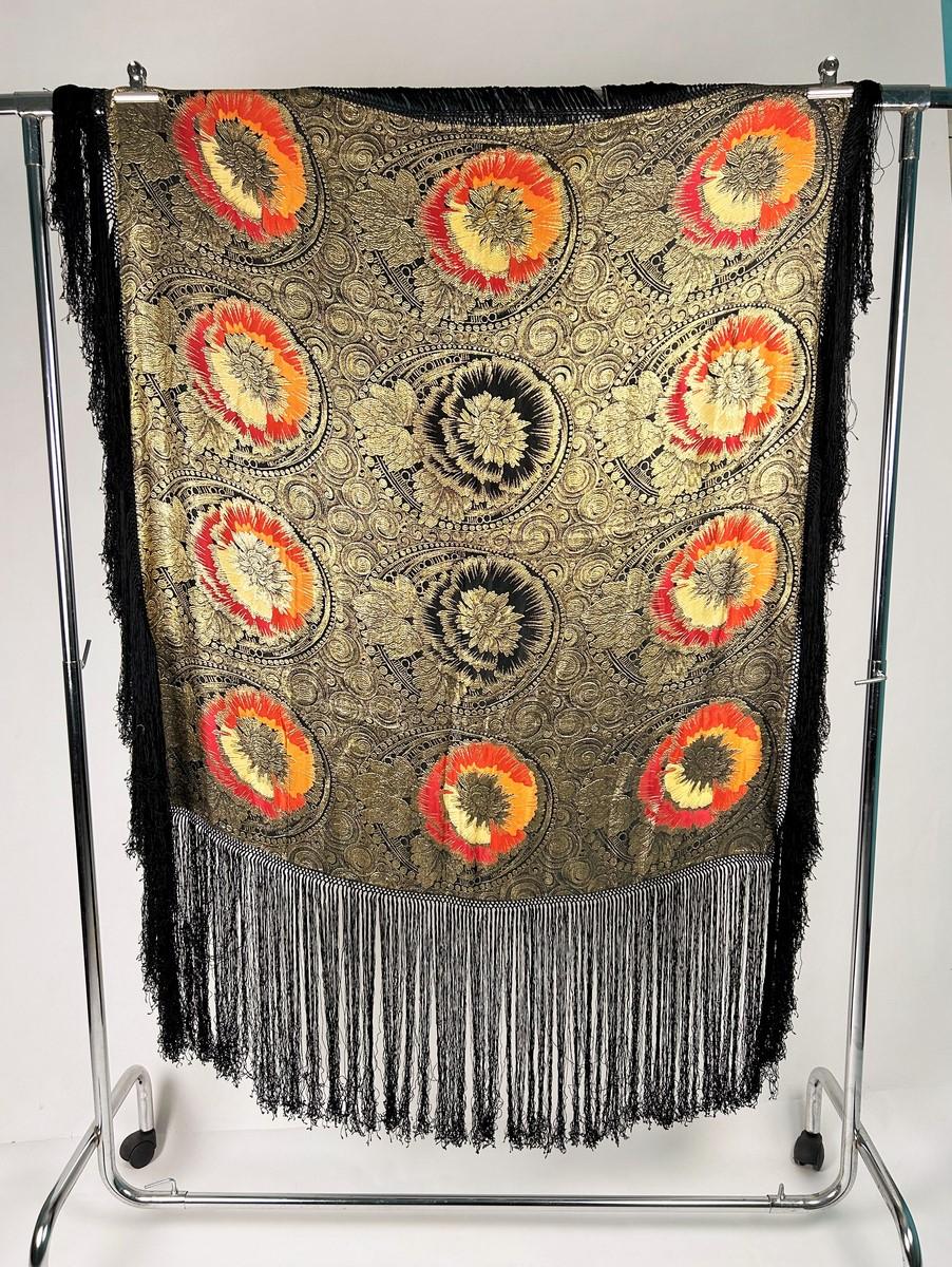 Alrededor de 1925
Francia
Espectacular chal de noche de lamé dorado de la época Art Déco en Francia. Chal cuadrado con diseño reversible, tejido ribeteado con lamé dorado sobre fondo de satén negro. Doce grandes flores en flor en tonos rojo,