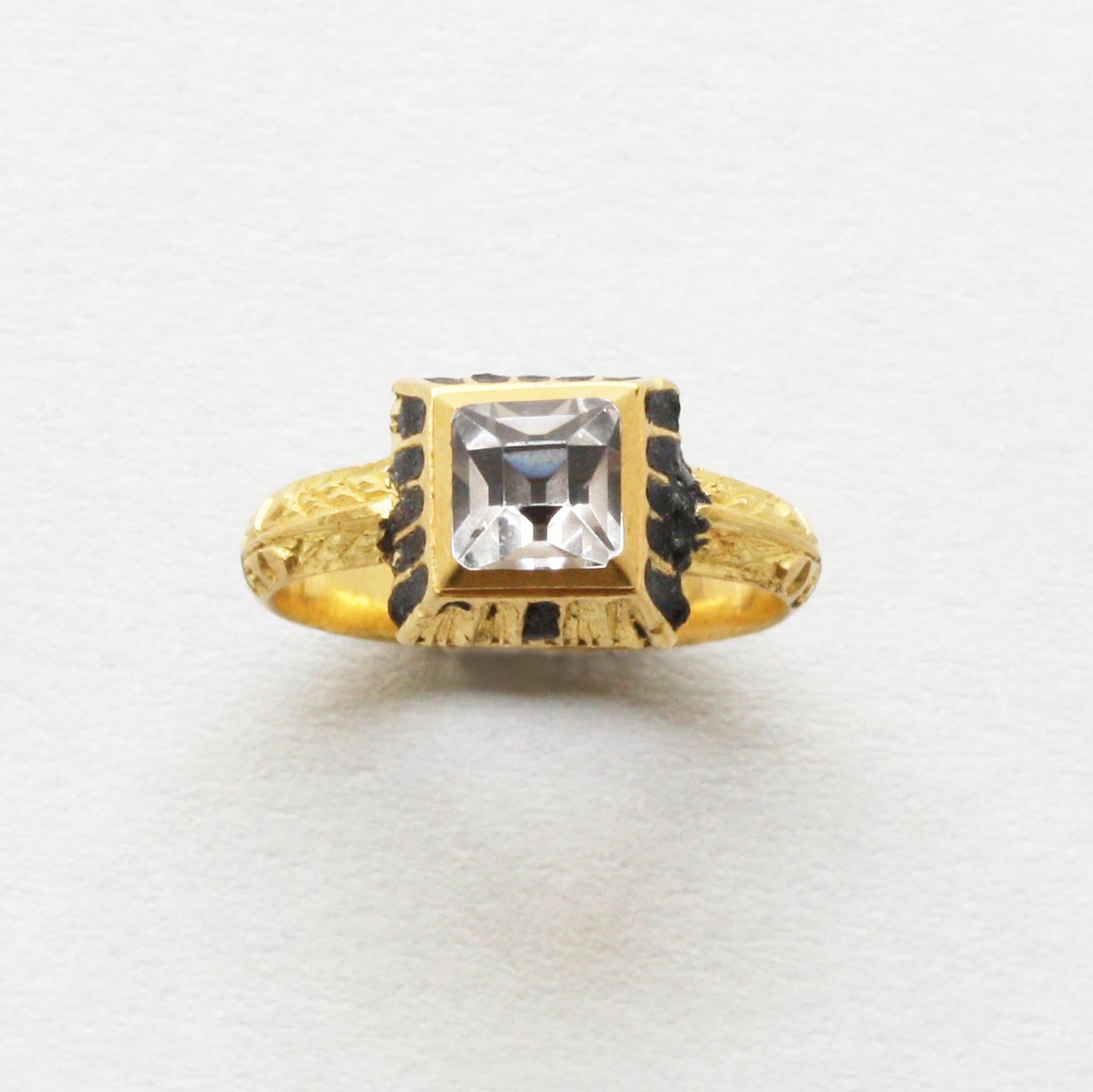 A gold ring set with a table cut rock crystal in a box setting which sides are decorated with black enamel and scrolls on the shank, marked with a star, Netherlands, circa 1600.

PAN registration number: 00078640.

ring size: 16.25 mm / 5 ¾