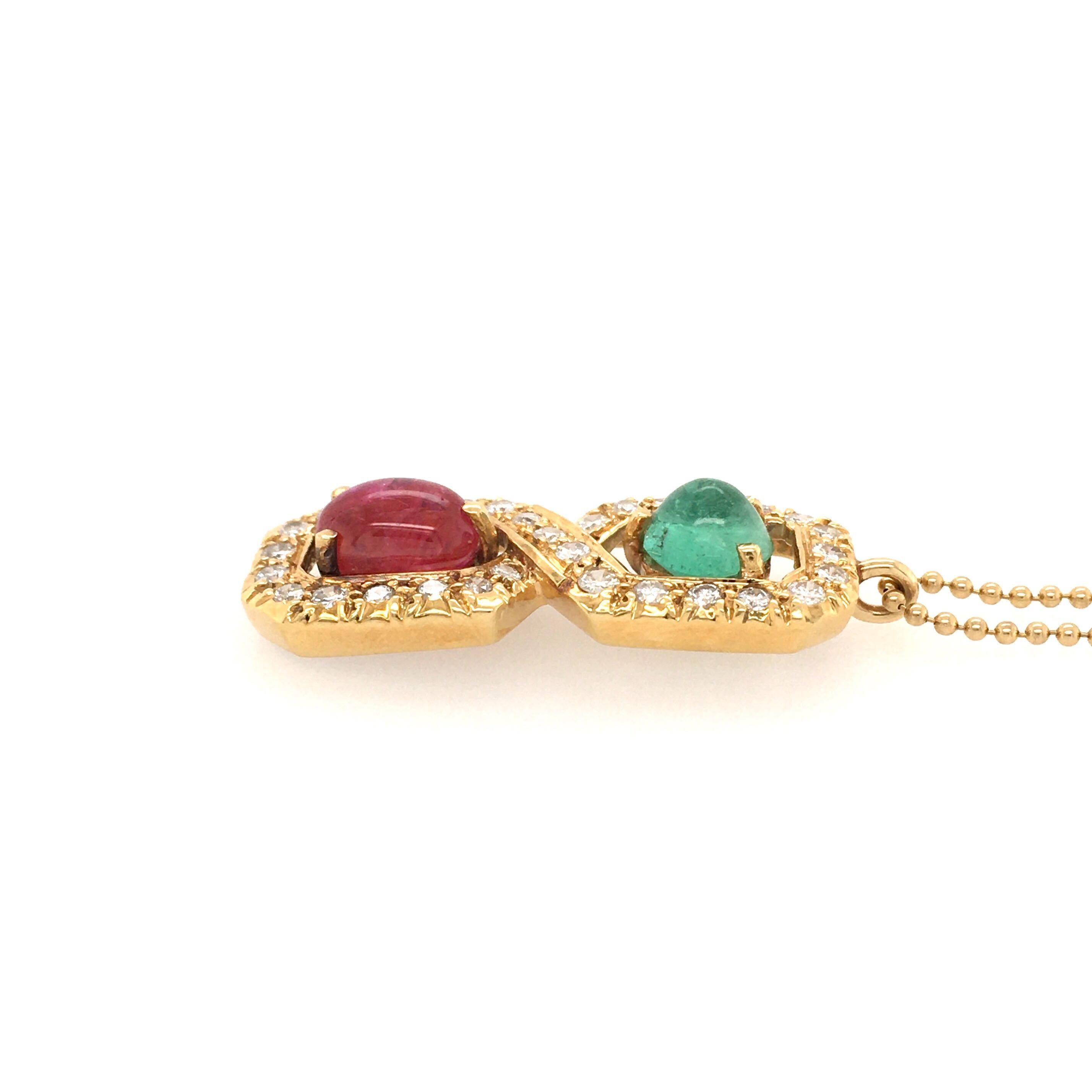 An 18 karat yellow gold, ruby, emerald and diamond pendant, with 14 karat yellow gold bead chain. Designed as a circular cut diamond set figure 8 pendant, set with an oval cabochon ruby, weighing approximately 2.40 carats and a circular sugarloaf