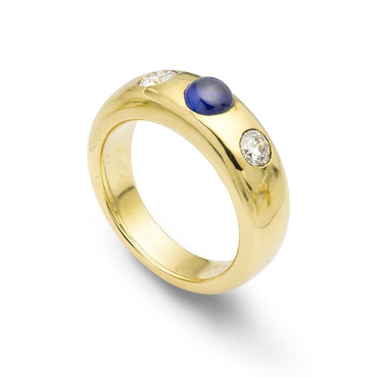 A gold sapphire and diamond gypsy ring, the cabochon-cut sapphire,  weighing 0.94 carats, set horizontally with a round brilliant-cut diamond to each side, weighing a total of 0.48 carats, all gypsy set to a yellow mount with a tapering band,