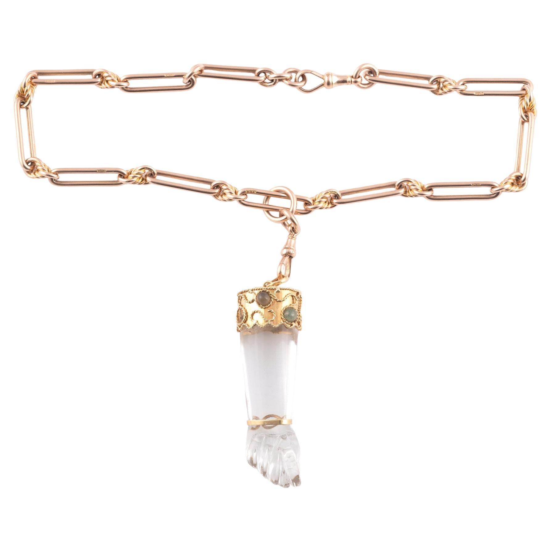Composed of 9 carat yellow gold fancy links and an crystal hand realistically modelled with the thumb between the first two fingers surmounted by a gold cap embellished with cabochon cut semi-precious stones, length 80mm including loop.
Necklace