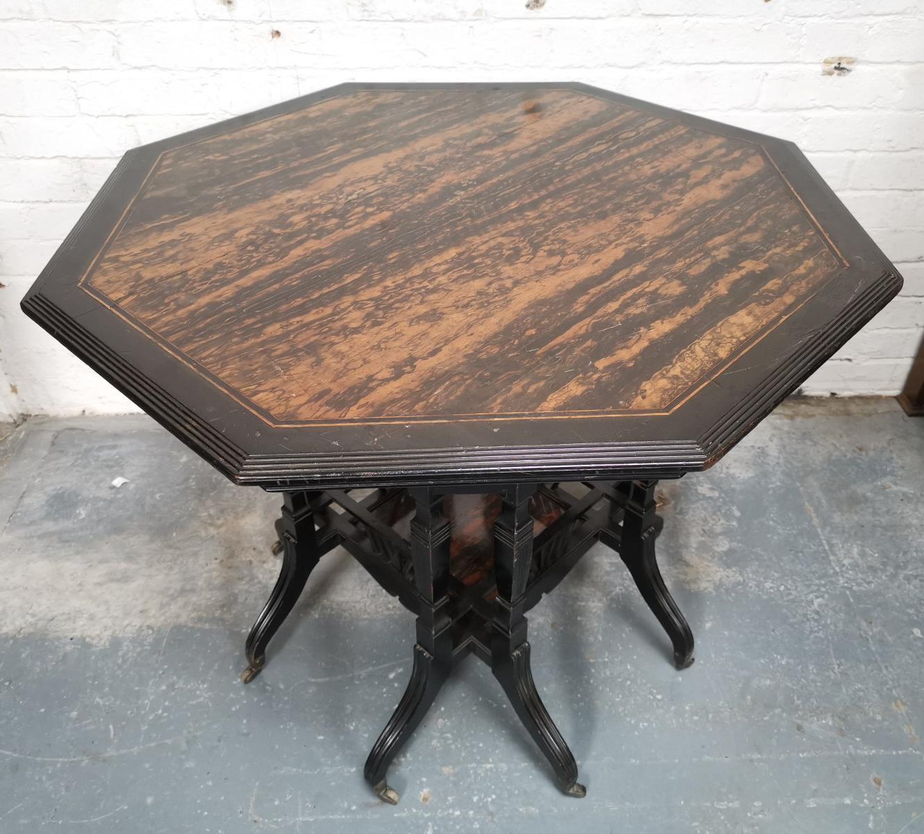 Lambs of Manchester. A rare Aesthetic Movement ebonized walnut octagonal eight-leg centre table with a veneered macassar ebony top and a molded edge and shaped aprons below united by four upper turned stretchers, the centre of the lower shelf with