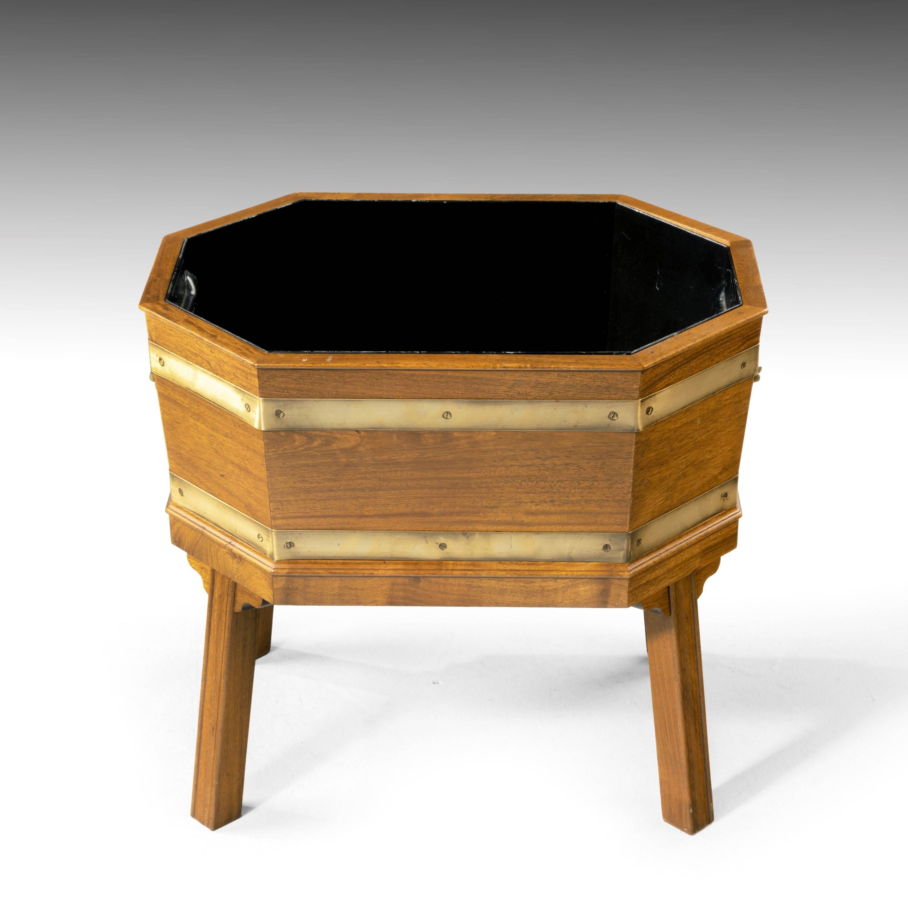 A George III style brass banded octagonal planter. Originally for wine and now with an interior liner. Supported on four channeled moulded legs. With brass carrying handles to the sides and good brass banding all around.
  