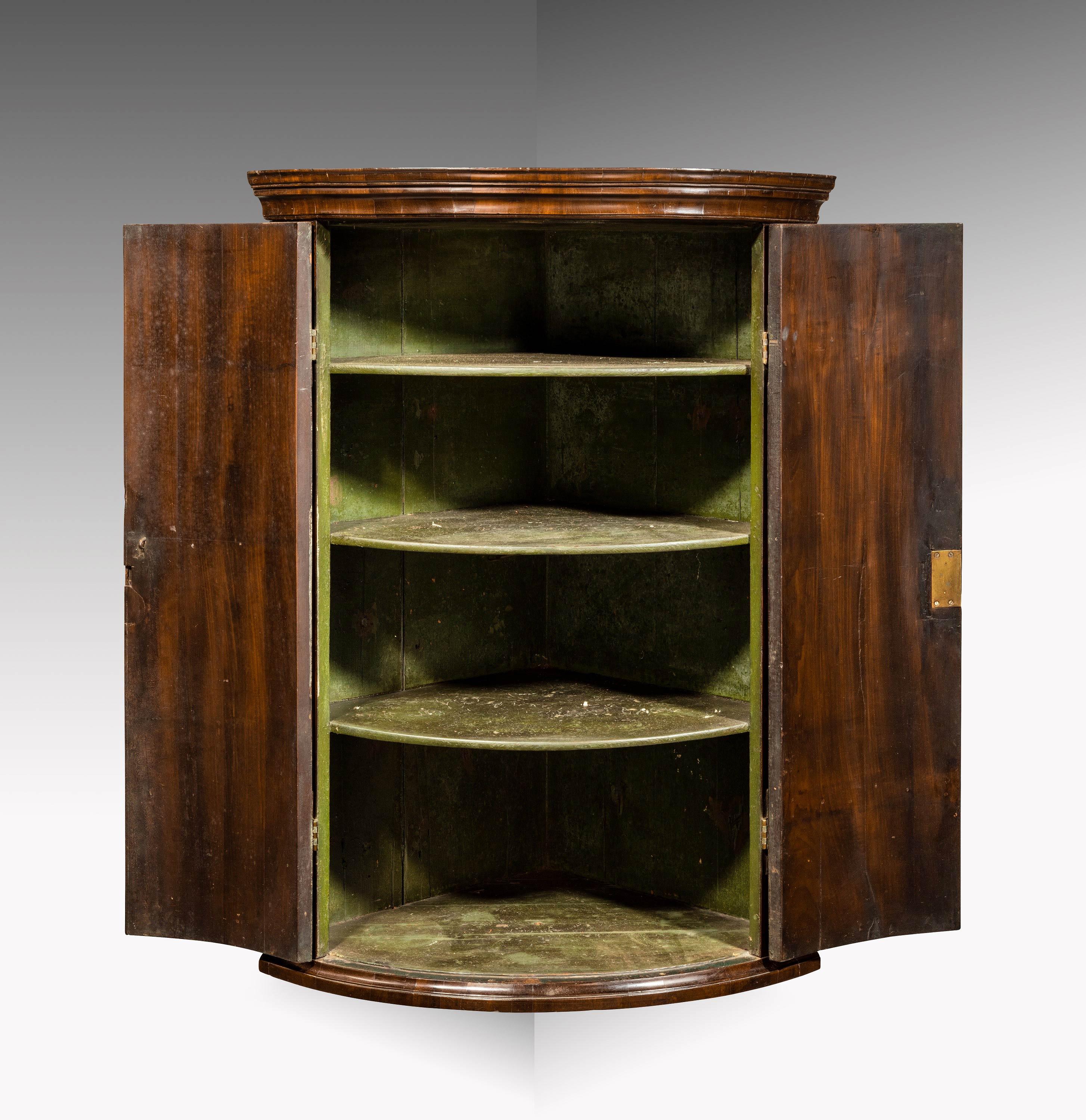 A good George III period bow fronted mahogany corner cupboard. Of excellent colour and patina. The interior retaining three original fixed shelves. Original H-hinges and shaped escutcheons..
  