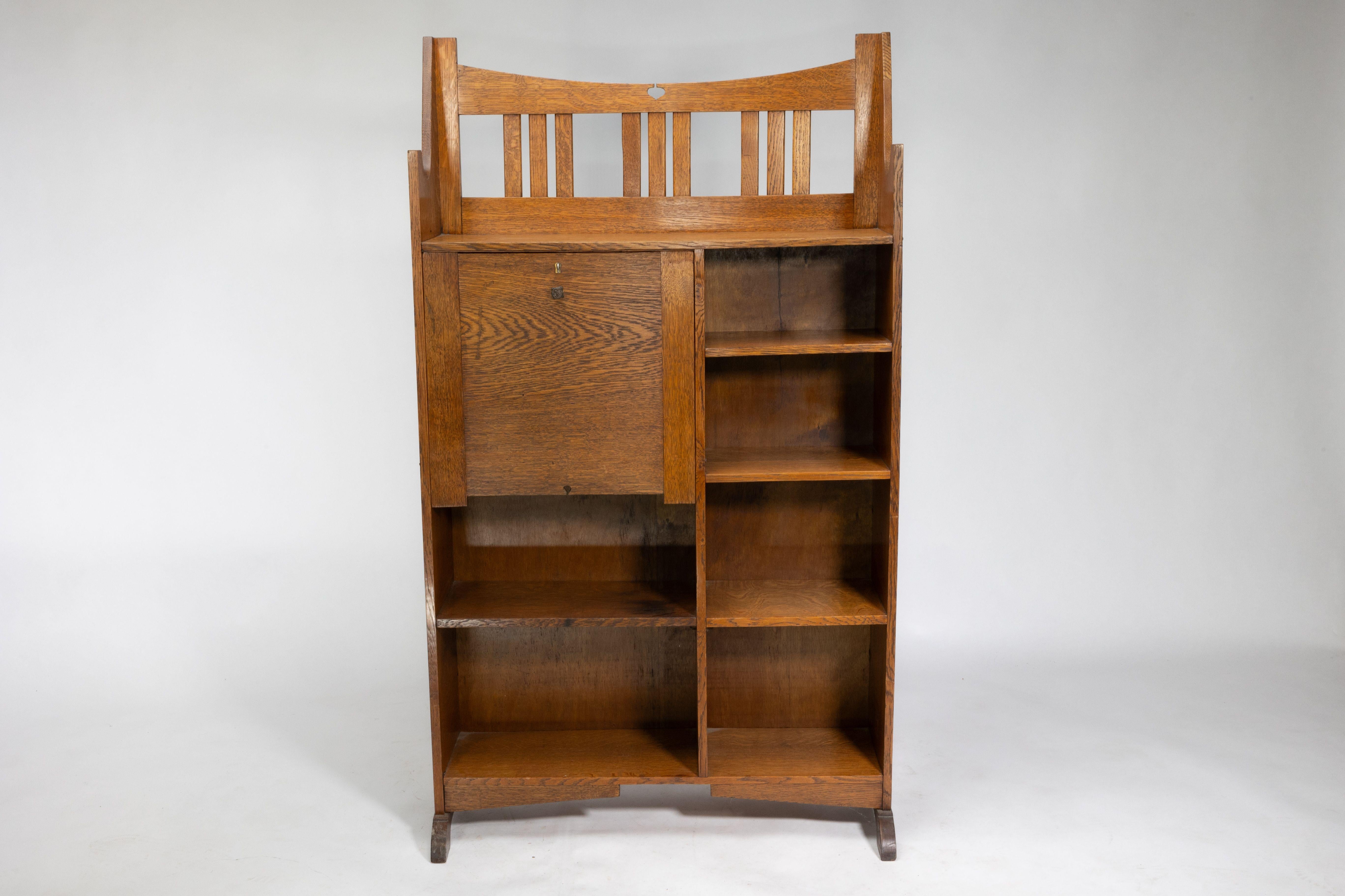 A good Glasgow School bureau bookcase with pierced detail to the sweeping slatted top. A small fold down writing area with further cut-out to the bottom and a bank of four bookshelves to the right.