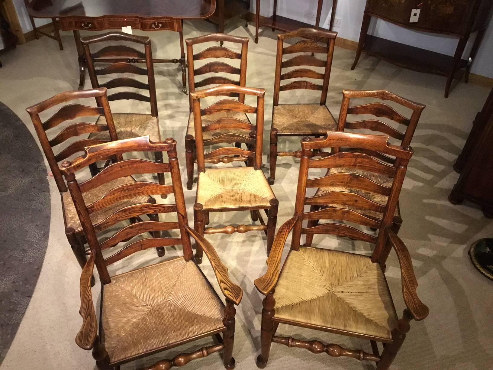 A good harlequin set of eight ash and elm mid-19th century Billinge ladder back dining chairs including two carver arm chairs with six shaped ladder back rungs, open swept arms, rush seats and turned front supports united by H stretchers. The Stand
