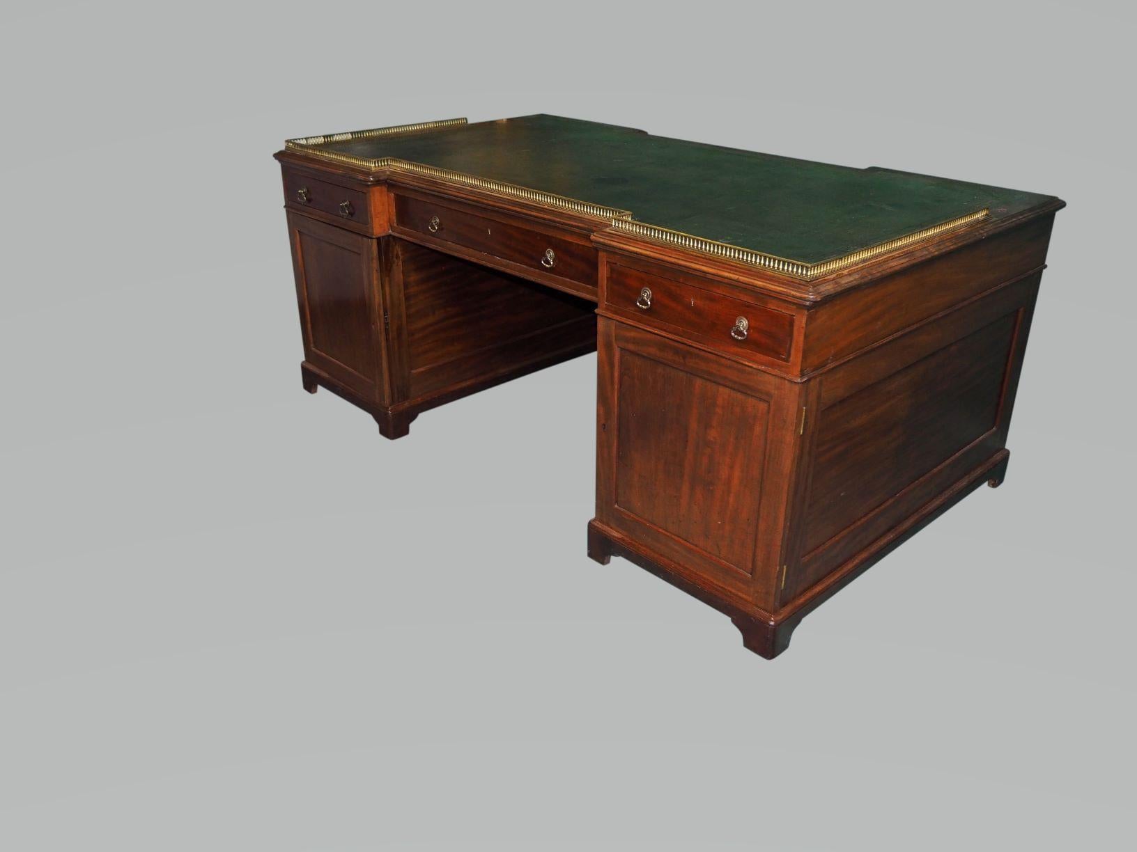 A Good Large double pedesal mahogany partners desk , with brass gallery to the top the gallery supports simulating corinthian columns, The original dark green leather top with deep and intricate tooling embelllished with gilding , some of the gold