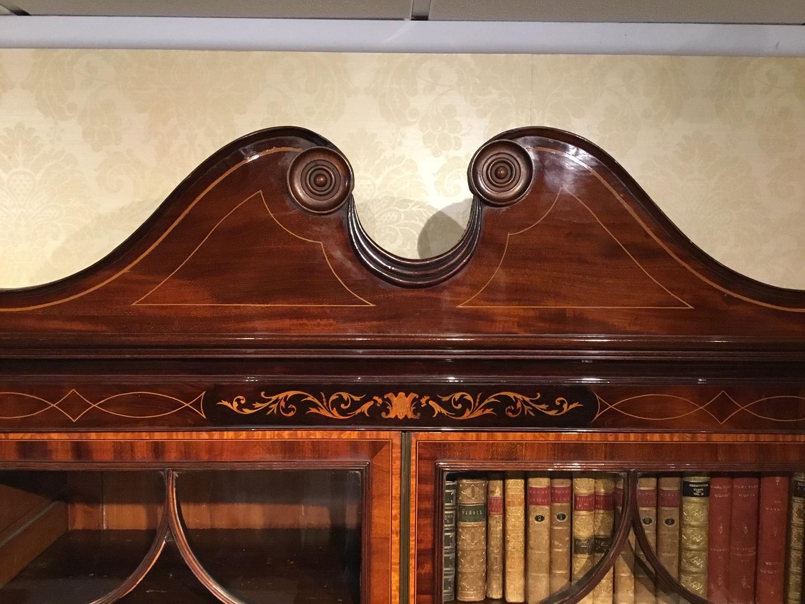 A good mahogany inlaid Edwardian period secretaire bookcase. The upper section has a broken swan neck pedestal with applied turned roundels and floral marquetry inlaid frieze. The twin astragal glazed doors having satinwood cross banding and triple