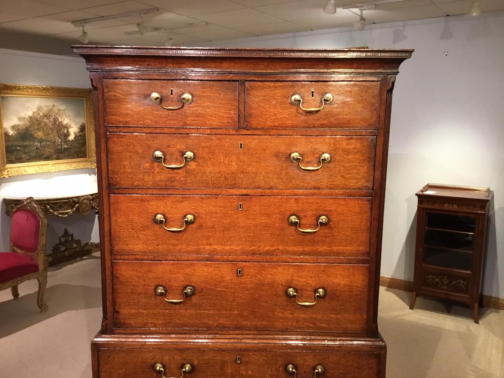 A good oak George III period antique chest on chest. The upper section with a Fine dog tooth inlaid cornice above an arrangement of two short and three long pine lined drawers and with reeded canted corners retaining the original brass handles. The