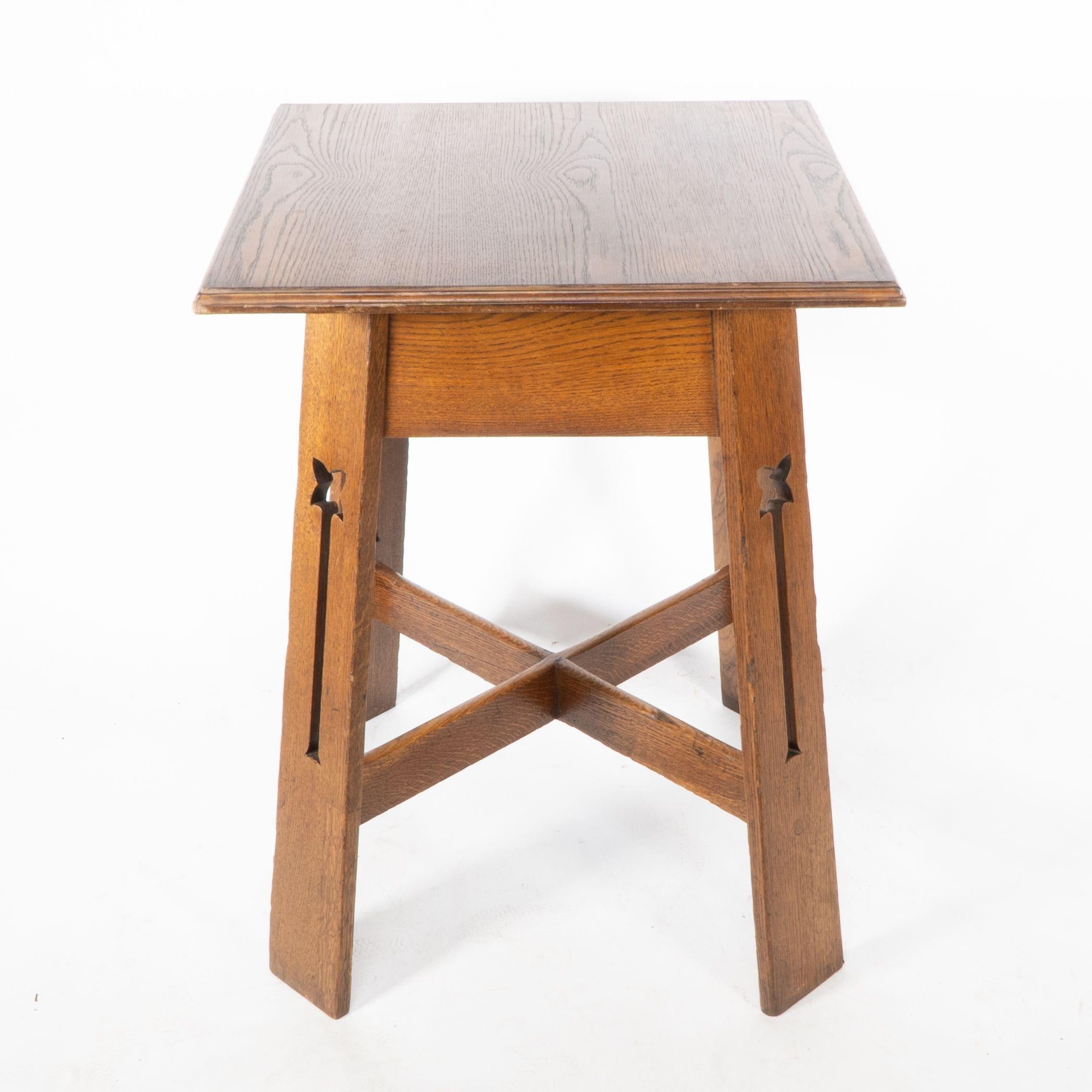 Una elegante mesa auxiliar Arts and Crafts de roble, de buena calidad, con estilizados recortes florales en cada pata y soportes cruzados que la convierten en una mesa muy robusta.