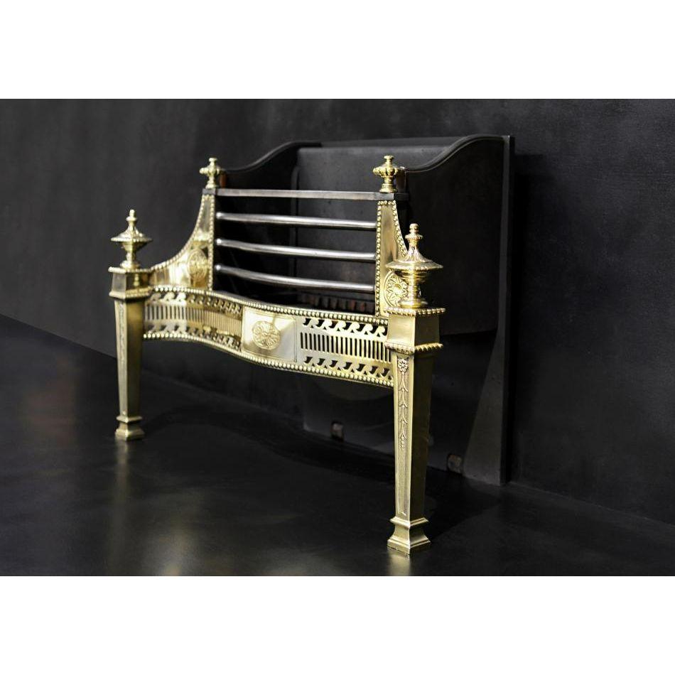 A good quality brass firegrate in the Georgian manner. The tapering legs with rosette and bellflower detailing, with classical finial above. The serpentine fret with fluting and scrollwork and engraved patera to centre. The polished steel front bars