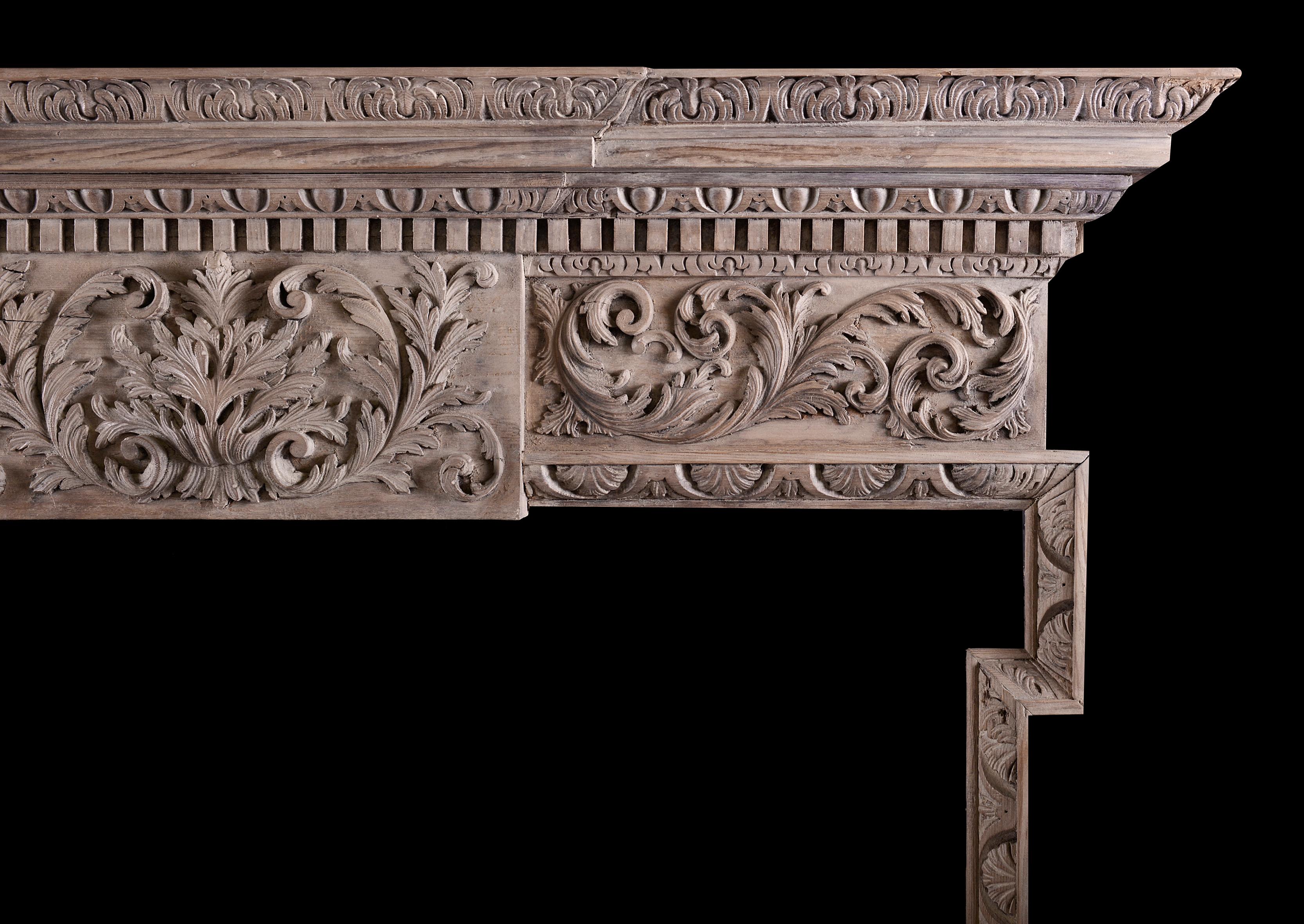 A good quality carved timber fireplace in the Georgian style. The jambs with crescent shaped shells throughout, the frieze with carved scrolls and foliage and elaborately carved centre plaque. The shelf with dentils, egg-and-tongue and acanthus