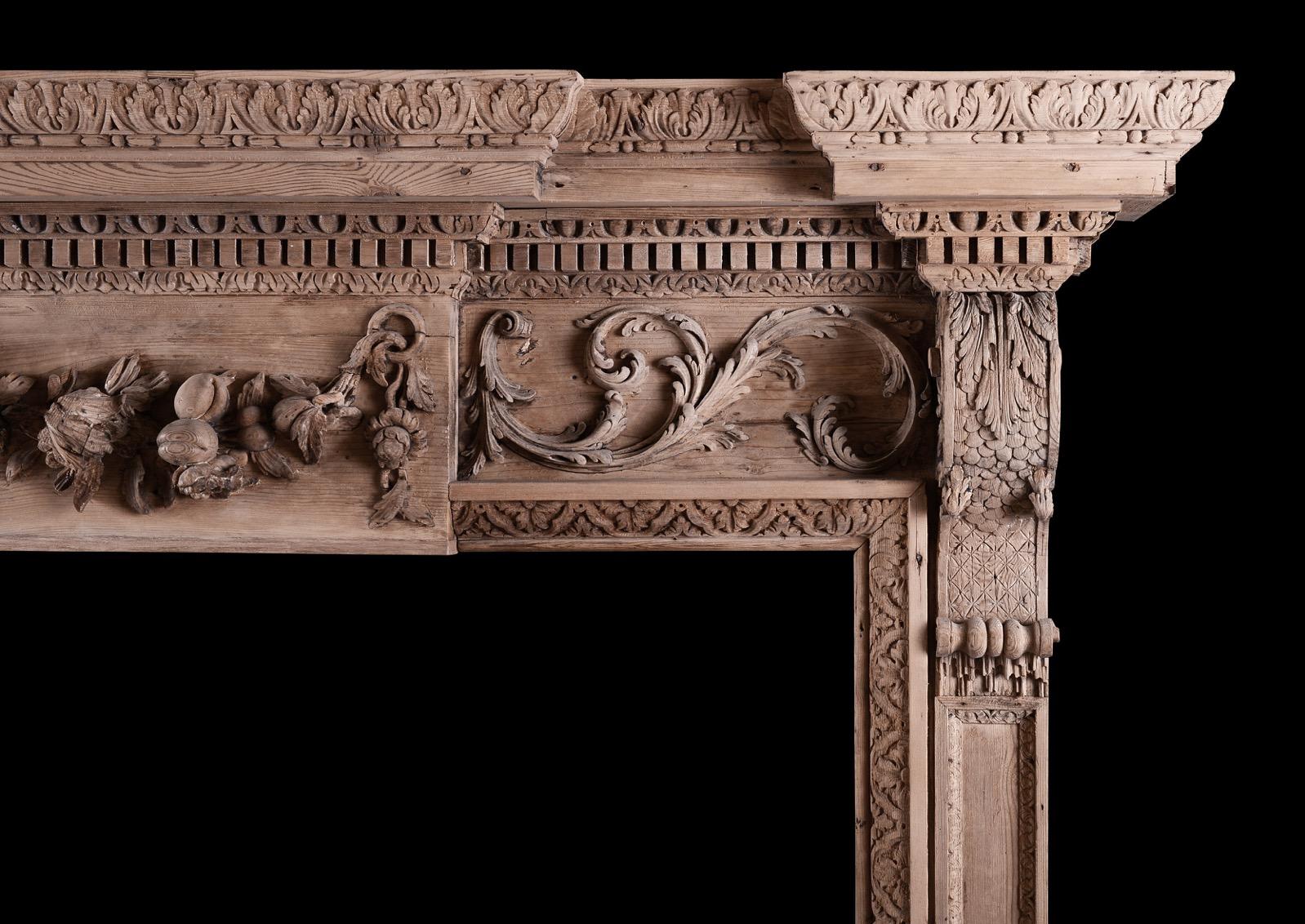 Une cheminée géorgienne en bois de bonne qualité. Les montants lambrissés sont surmontés de consoles à volutes sculptées de feuilles d'acanthe. La frise est ornée d'une plaque centrale sculptée de draperies, de fruits et de fleurs, flanquée de