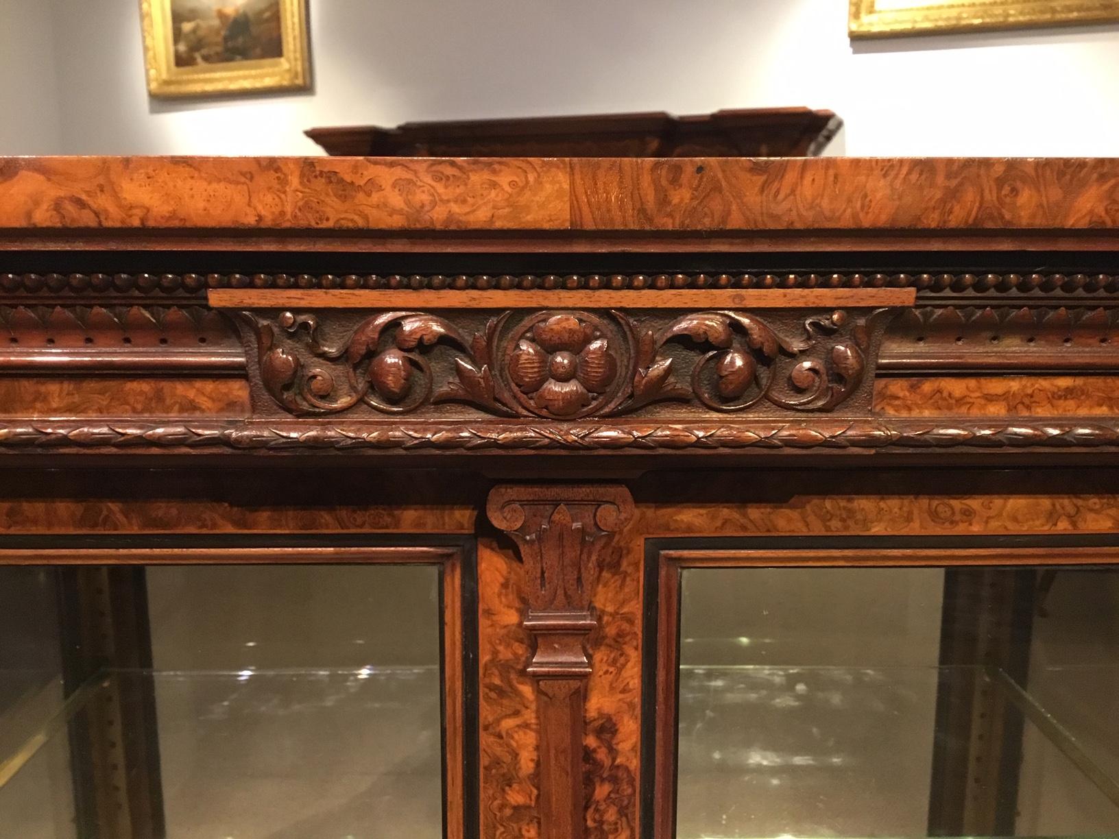 A good quality Victorian period burr walnut two-door display cabinet. The rectangular top veneered in the finest burr walnut veneers, above a beautifully hand carved frieze, with fine marquetry inlaid detail and finely carved walnut appliqués.