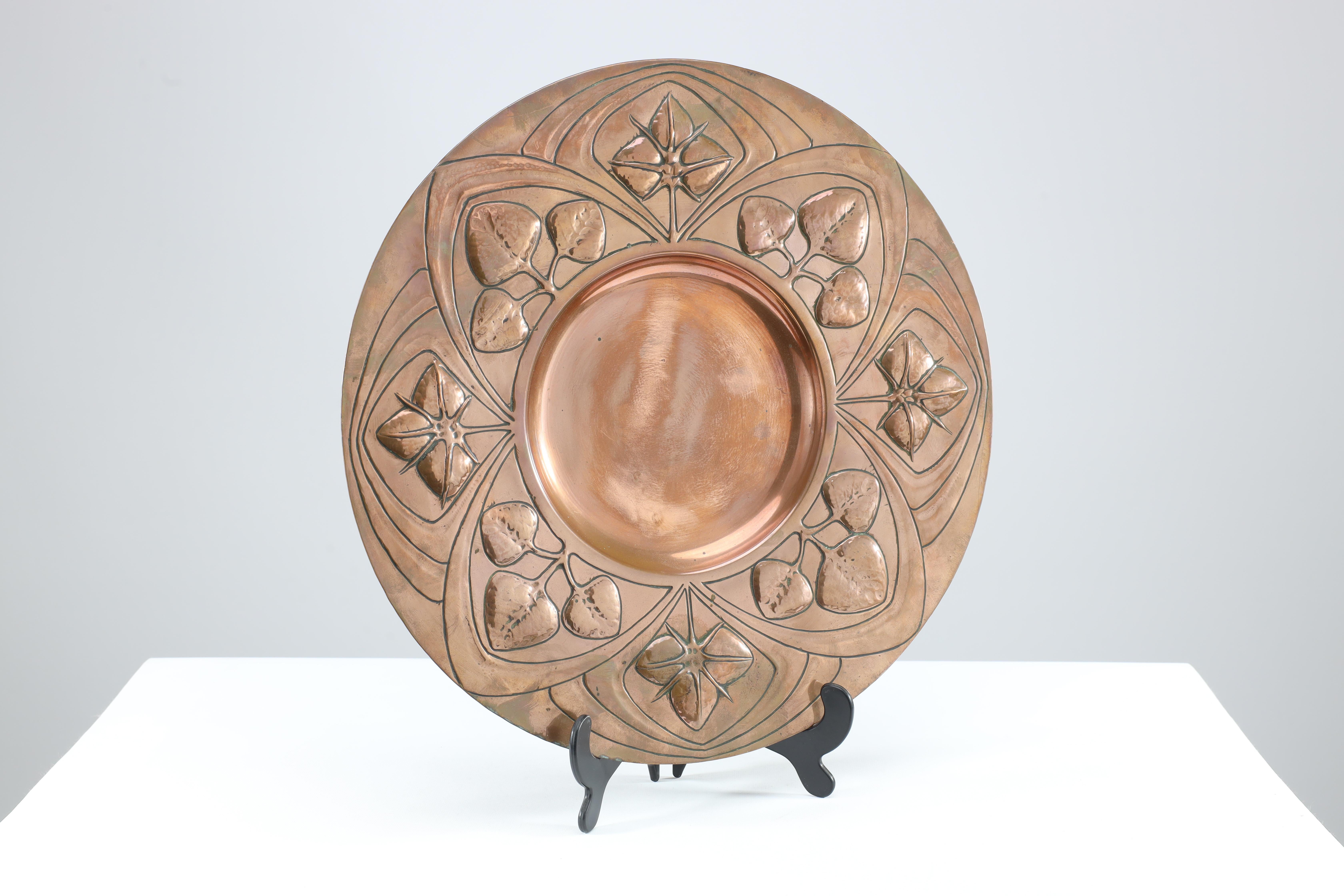 A good quality well executed Arts and Crafts copper wall plate with floral decoration around the centre.