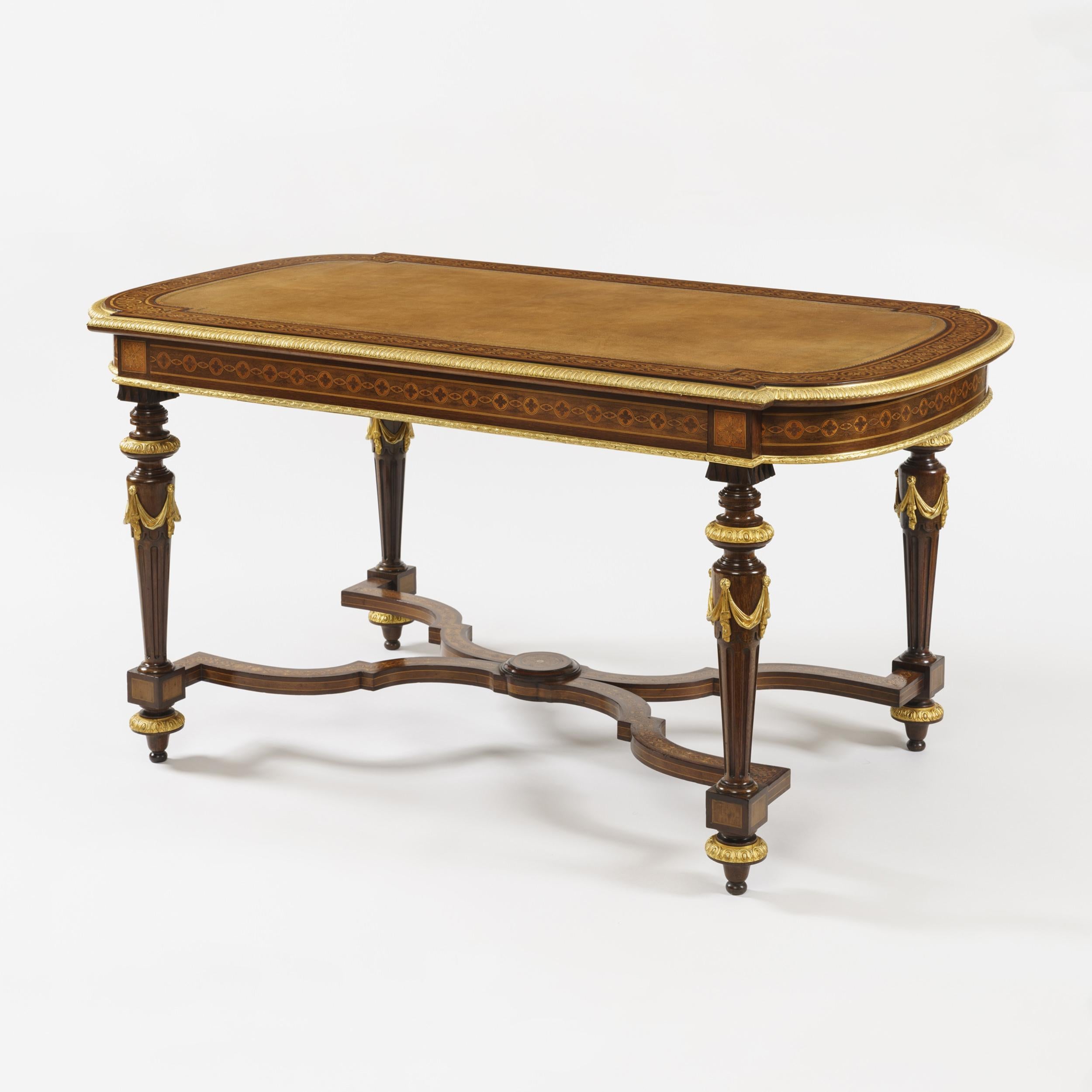 A good writing table in the Manner of Holland & Sons

Constructed in mahogany, with specimen wood inlays, and gilt bronze mounts; of rectangular form, with bowed ends, rising from ring turned, fluted and tapering legs, adorned with bronze swags and