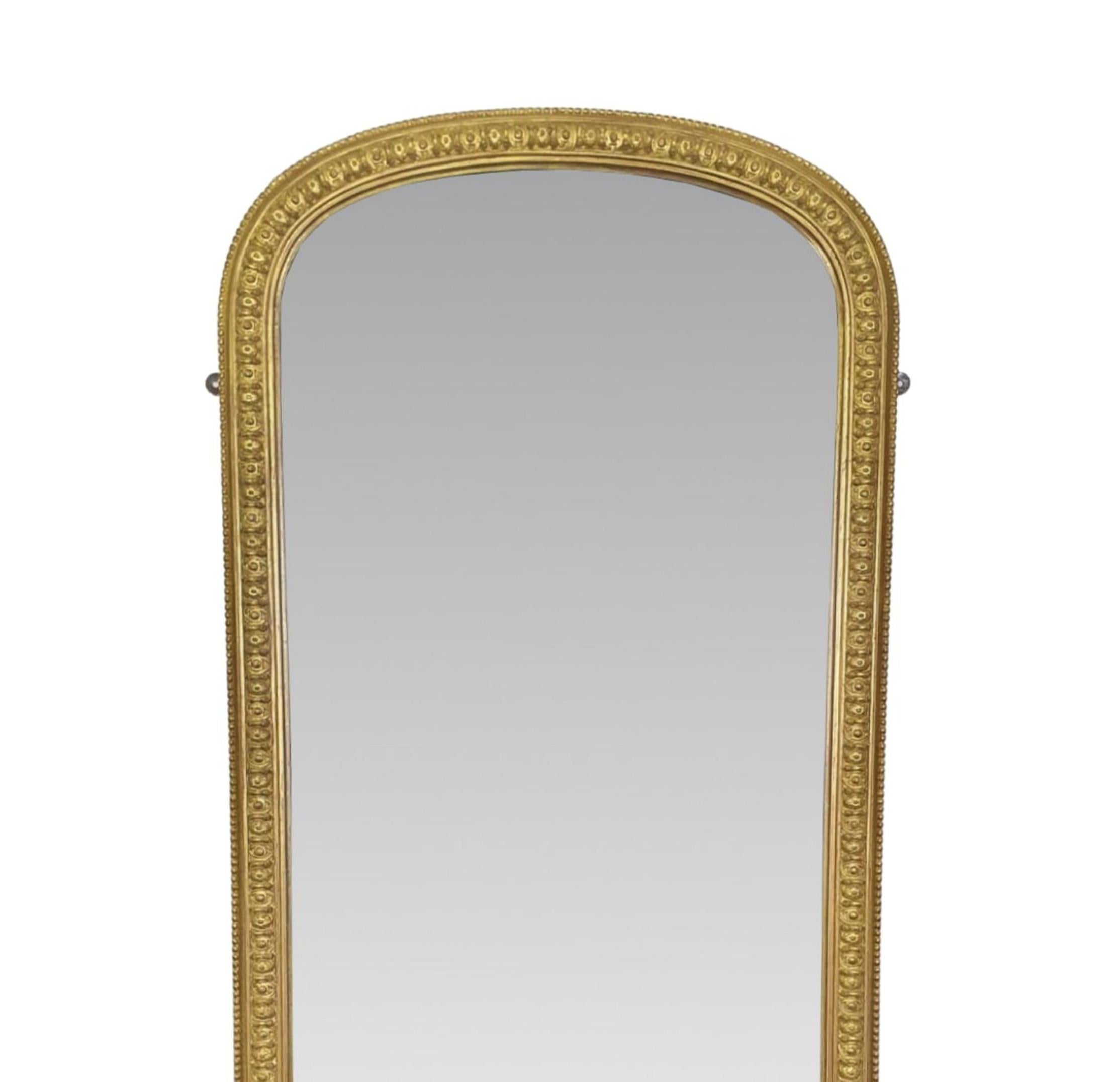 A gorgeous 19th century giltwood archtop pier or dressing mirror of tall and narrow proportions. The mirror glass plate set within a beautifully hand carved giltwood frame with reeding, bead and egg and dart motif detail sup-ported on platform base