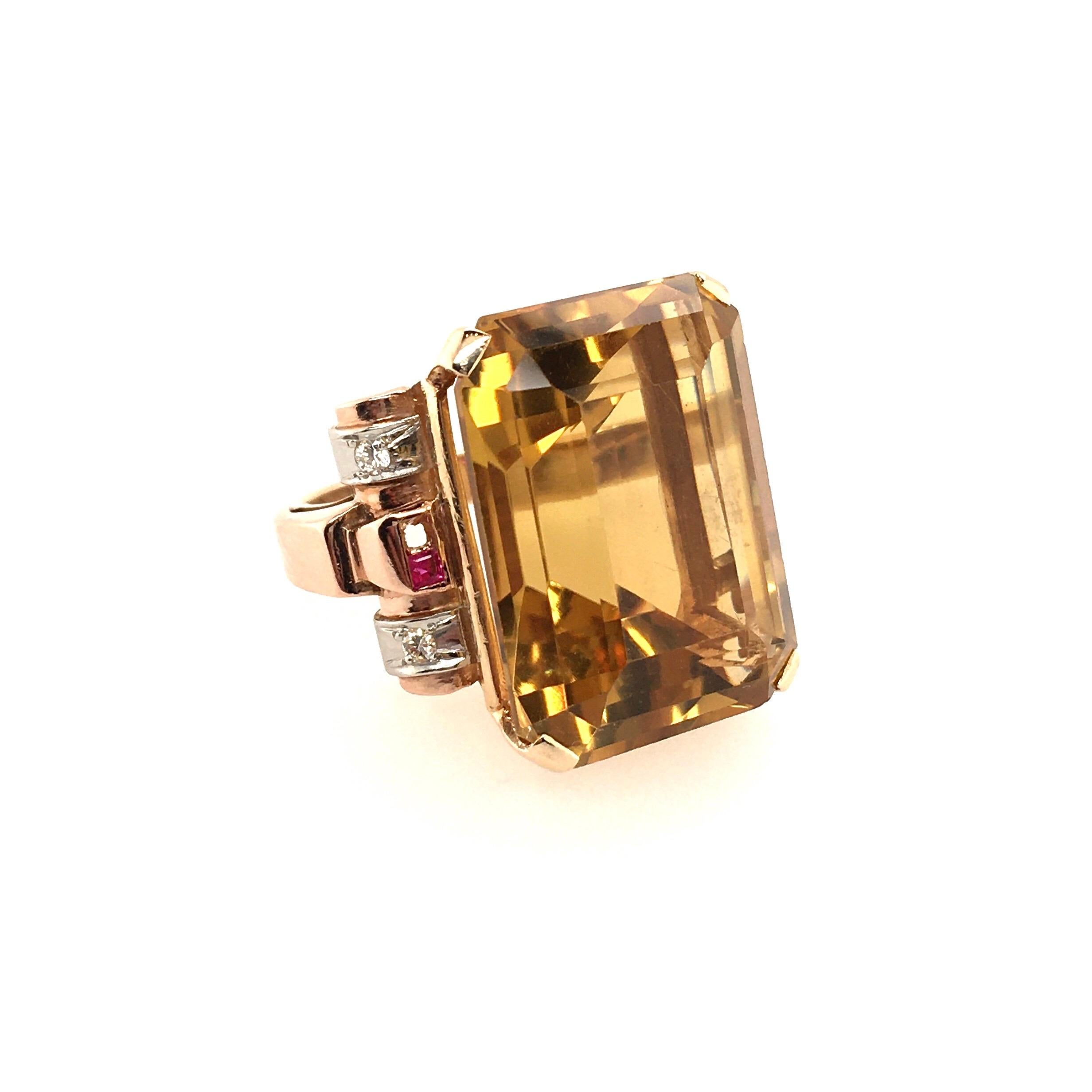  A 14 karat yellow gold, citrine, ruby and diamond ring. Circa 1940. Set with an emerald cut citrine, measuring approximately 22.5 x 17.0mm, enhanced by scroll shoulders, set with square cut ruby shoulders, enhanced by circular cut diamonds. Size 5,