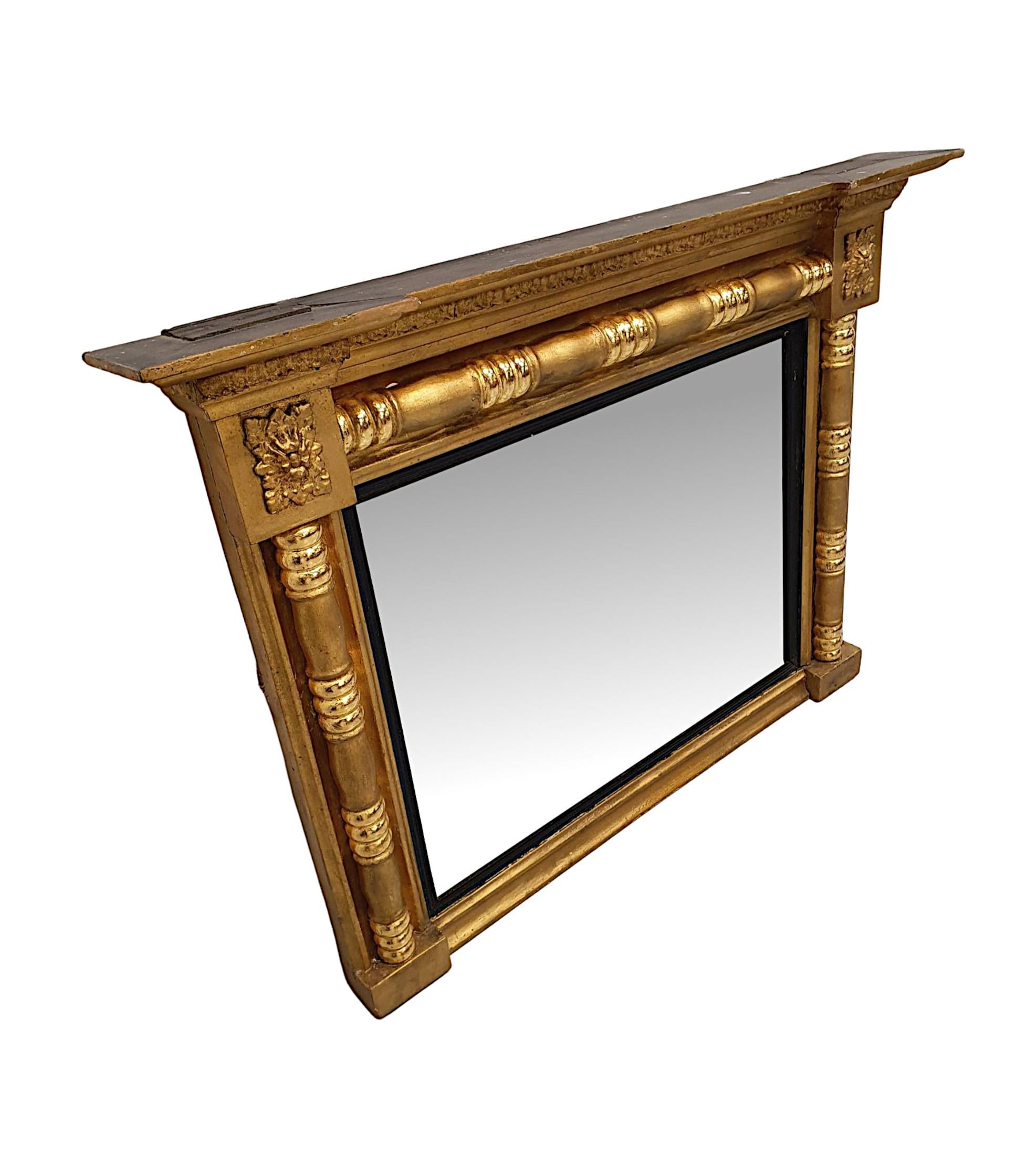 A gorgeous early 19th century giltwood overmantle mirror of neat proportions. The finely hand carved, moulded and fluted giltwood frame is surmounted with an overhanging broken pediment stepped cornice, raised above panelled frieze with beautifully