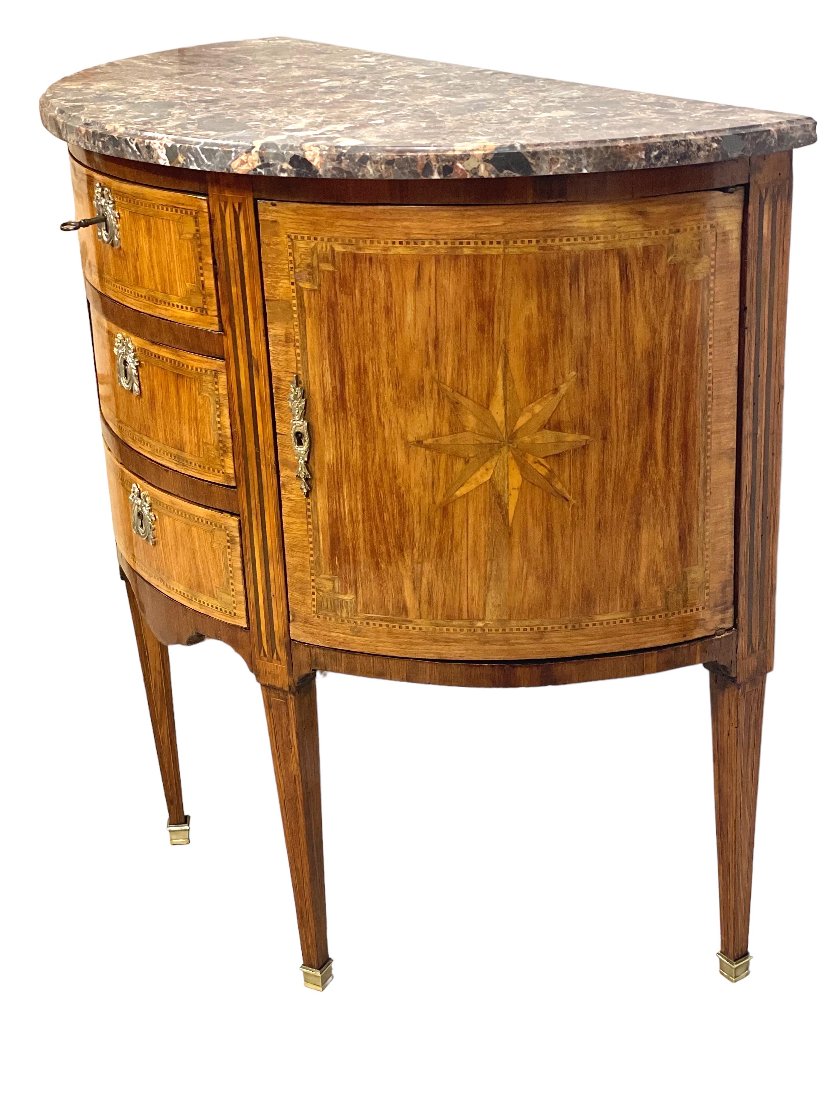 A gorgeous demi-lune (half-moon) shaped chest of drawers in wood veneer. Opening with three drawers and two side leaves, under a marble top, this attractive Louis XVI style commode would make a useful addition to a bedroom or hallway.