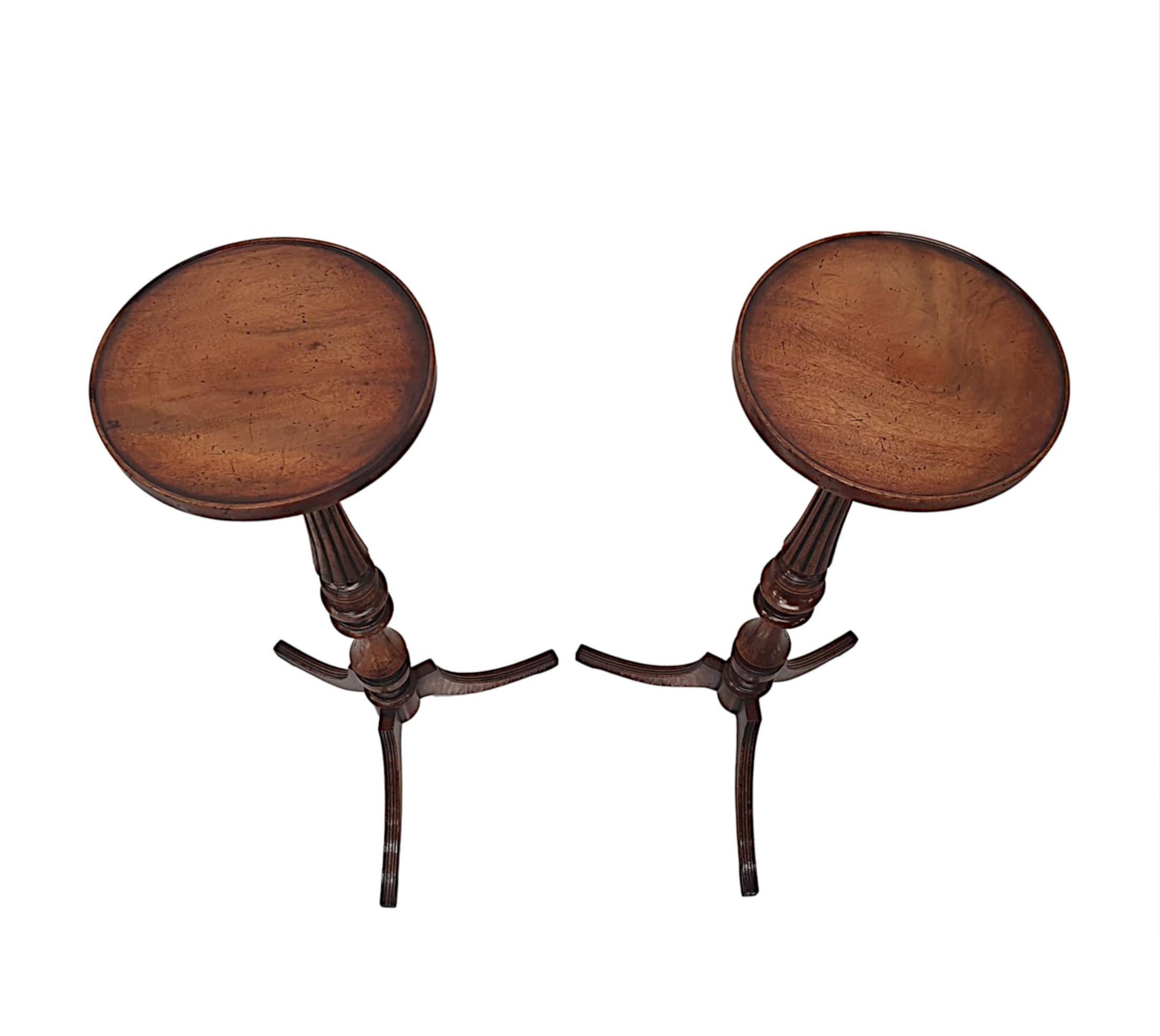A gorgeous pair of 20th Century richly patinated mahogany plant stands. The moulded top of circular form with gallery rim raised over a stunning slender ring turned pedestal column with fluted detail, supported on trefoil base with three elegant,