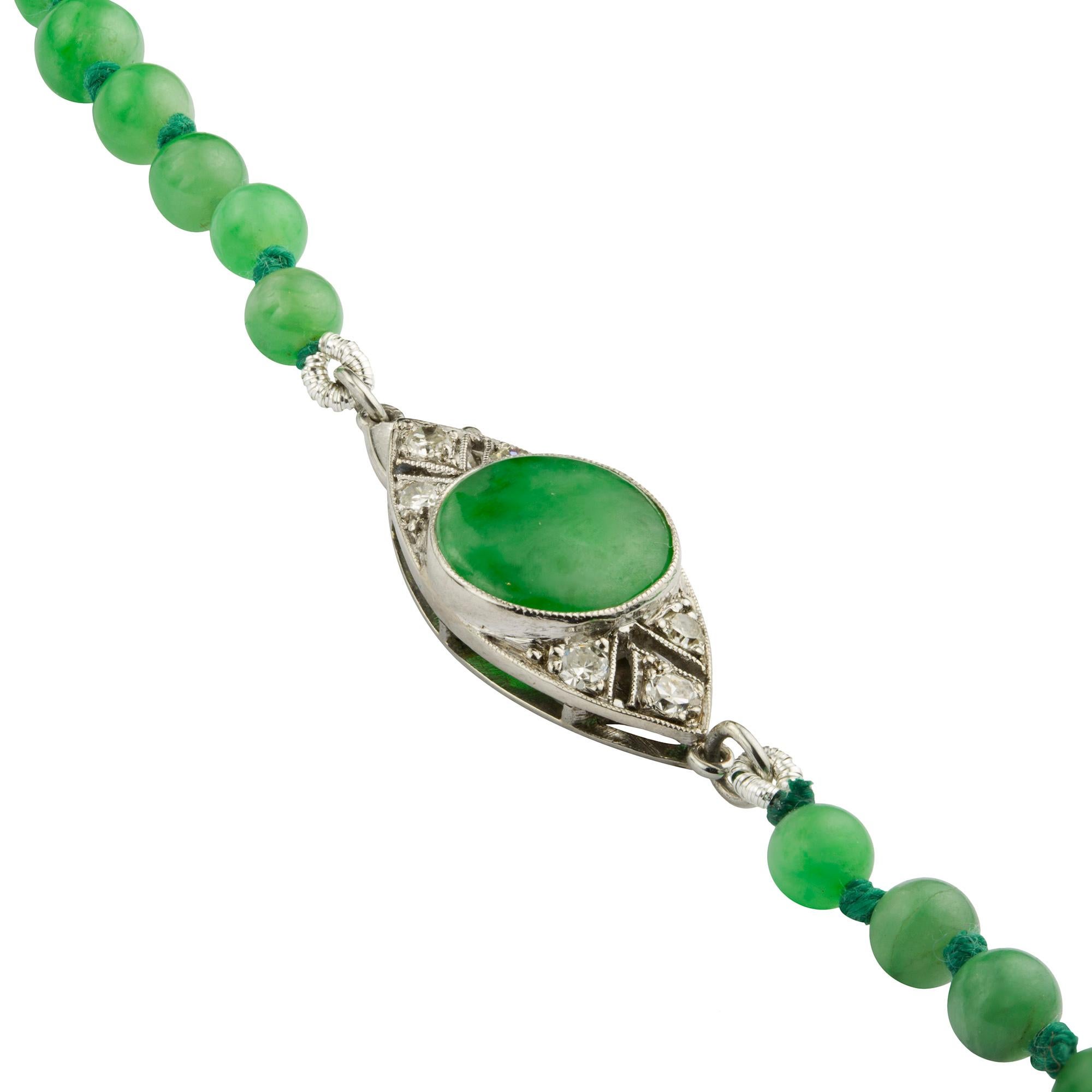 A graduate jadeite jade bead necklace with Art Deco clasp, the seventy-seven beads graduating from the centre, measuring approximately 9.3 to 3.8mm in diameter, all strung and knotted to an Art Deco navette-shaped clasp, centrally set with a round